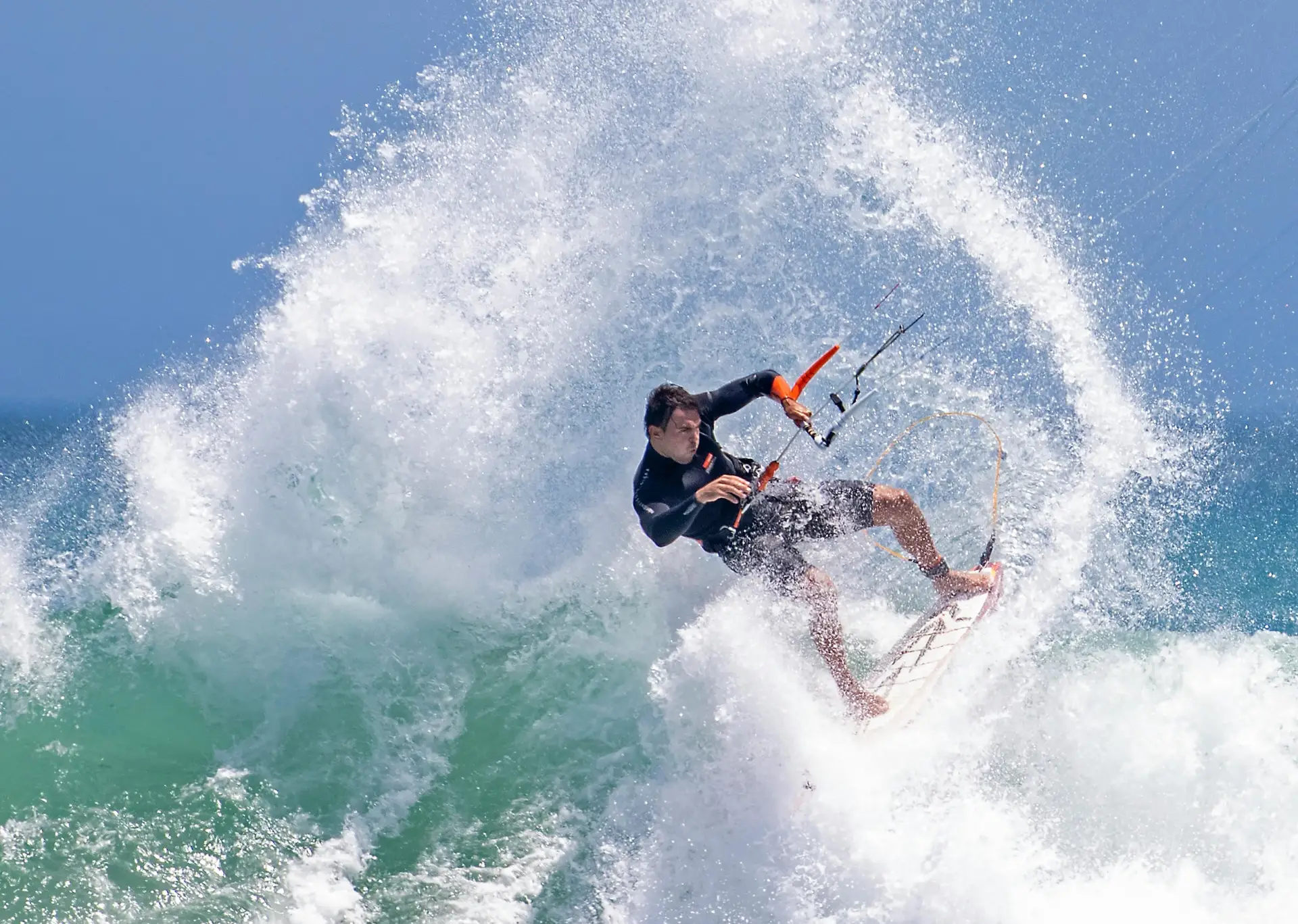 Kitesurfer en ola rompiente, con spray