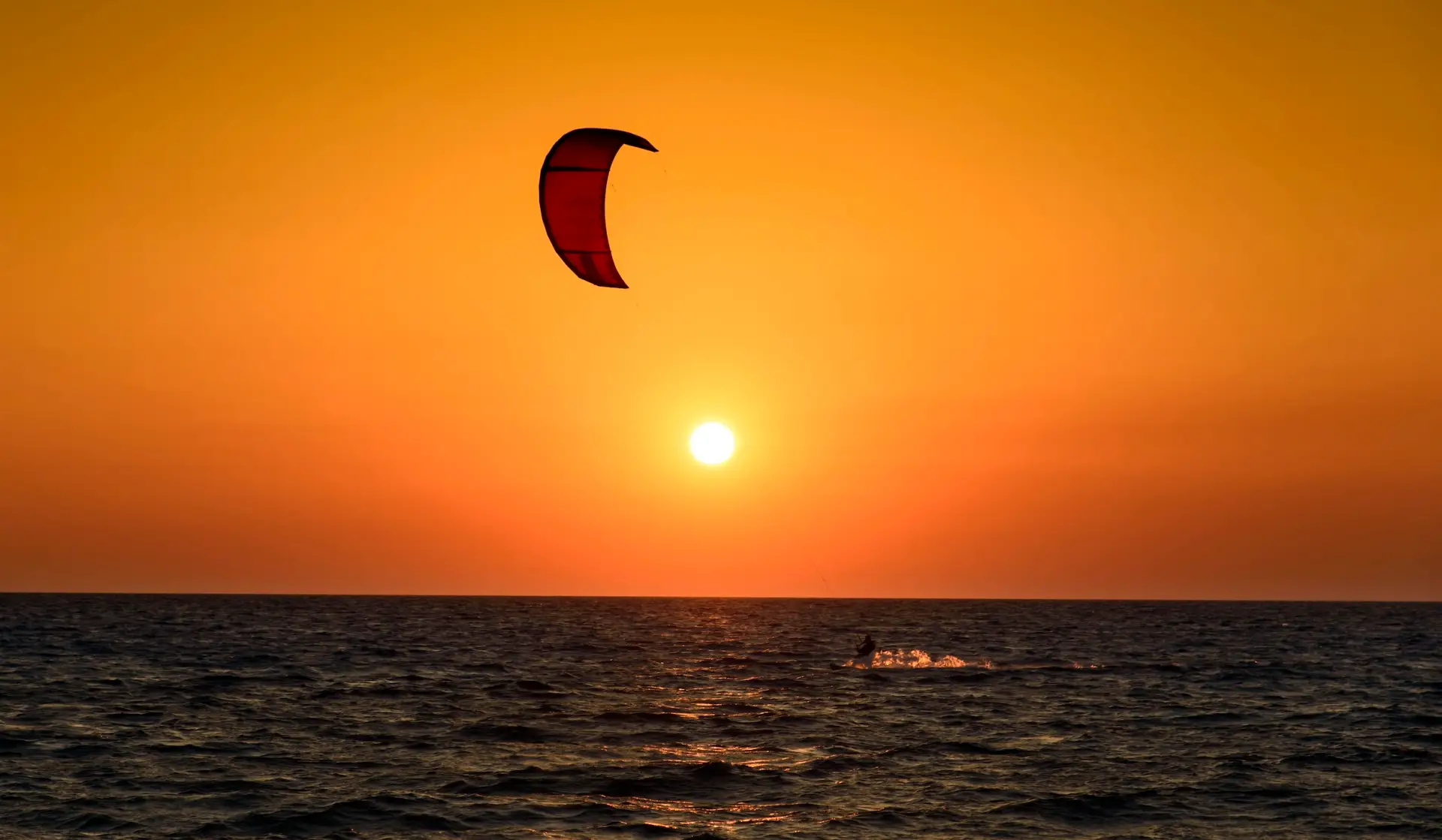 Kitesurfer en una ola a contraluz dorada