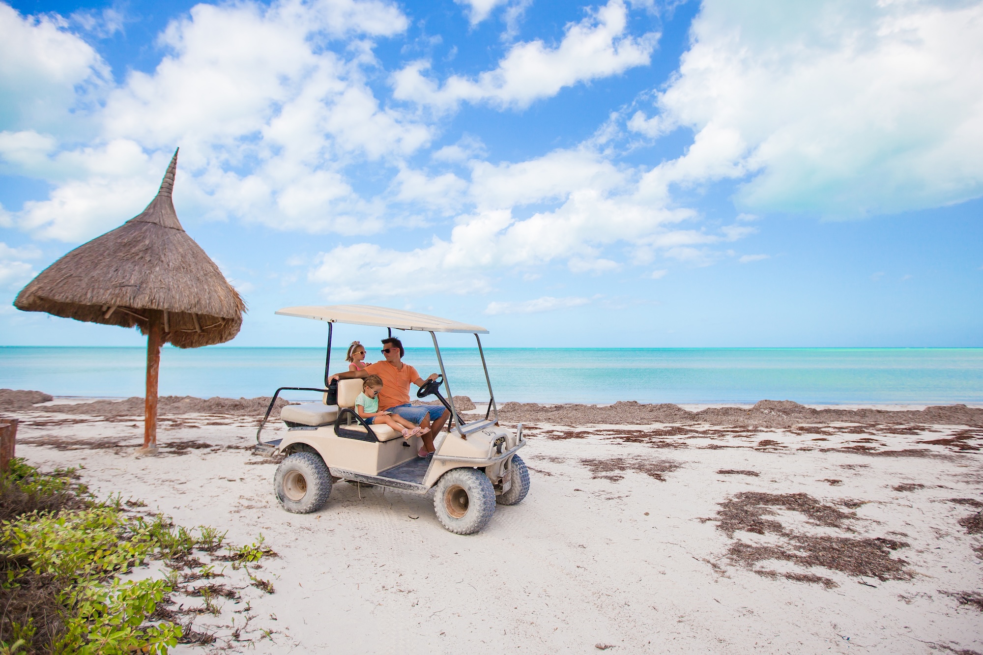 A family in a rented golf cart on a tropical island road