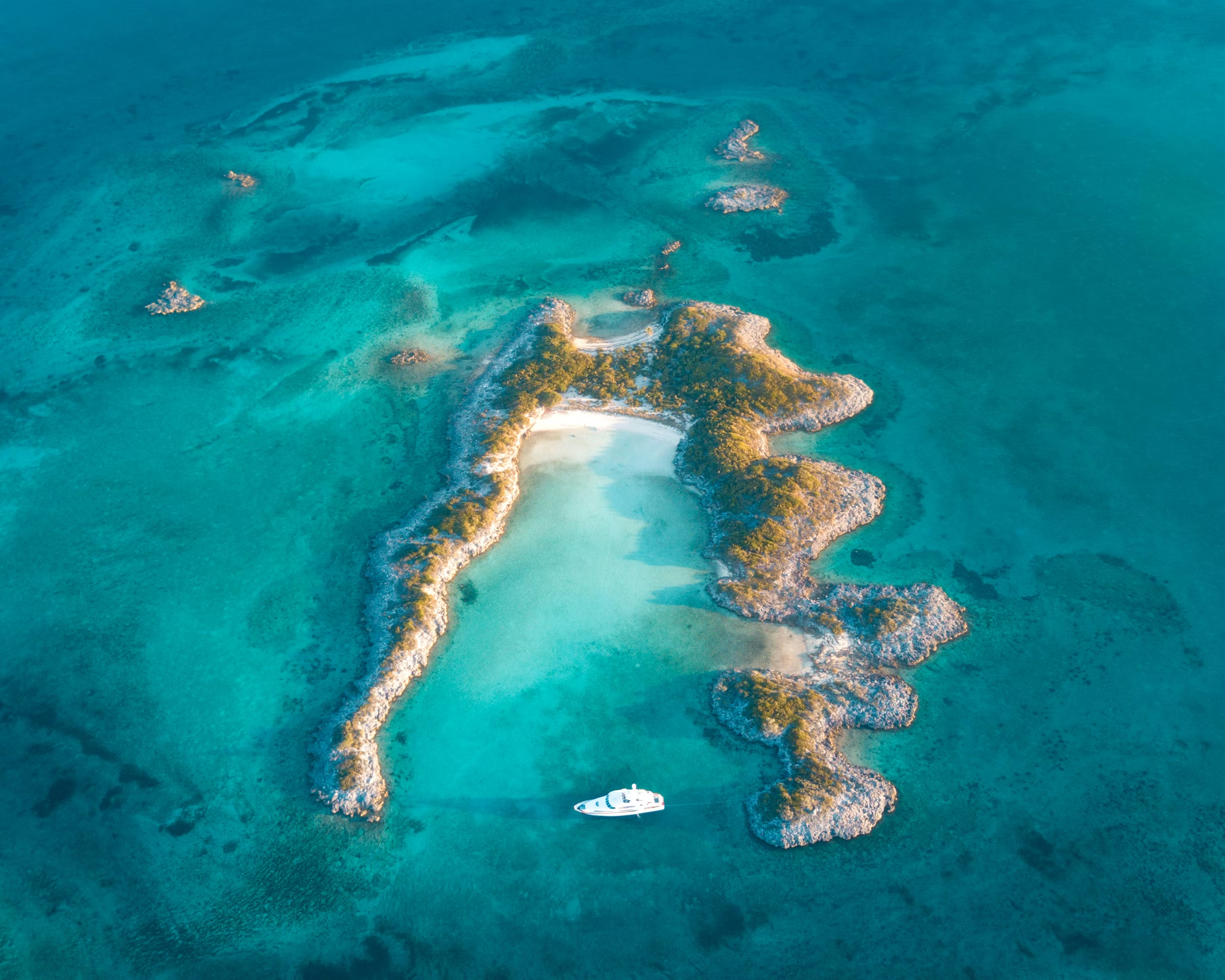 Aerial view of a yacht anchored in turquoise shallows surrounded by sandbars