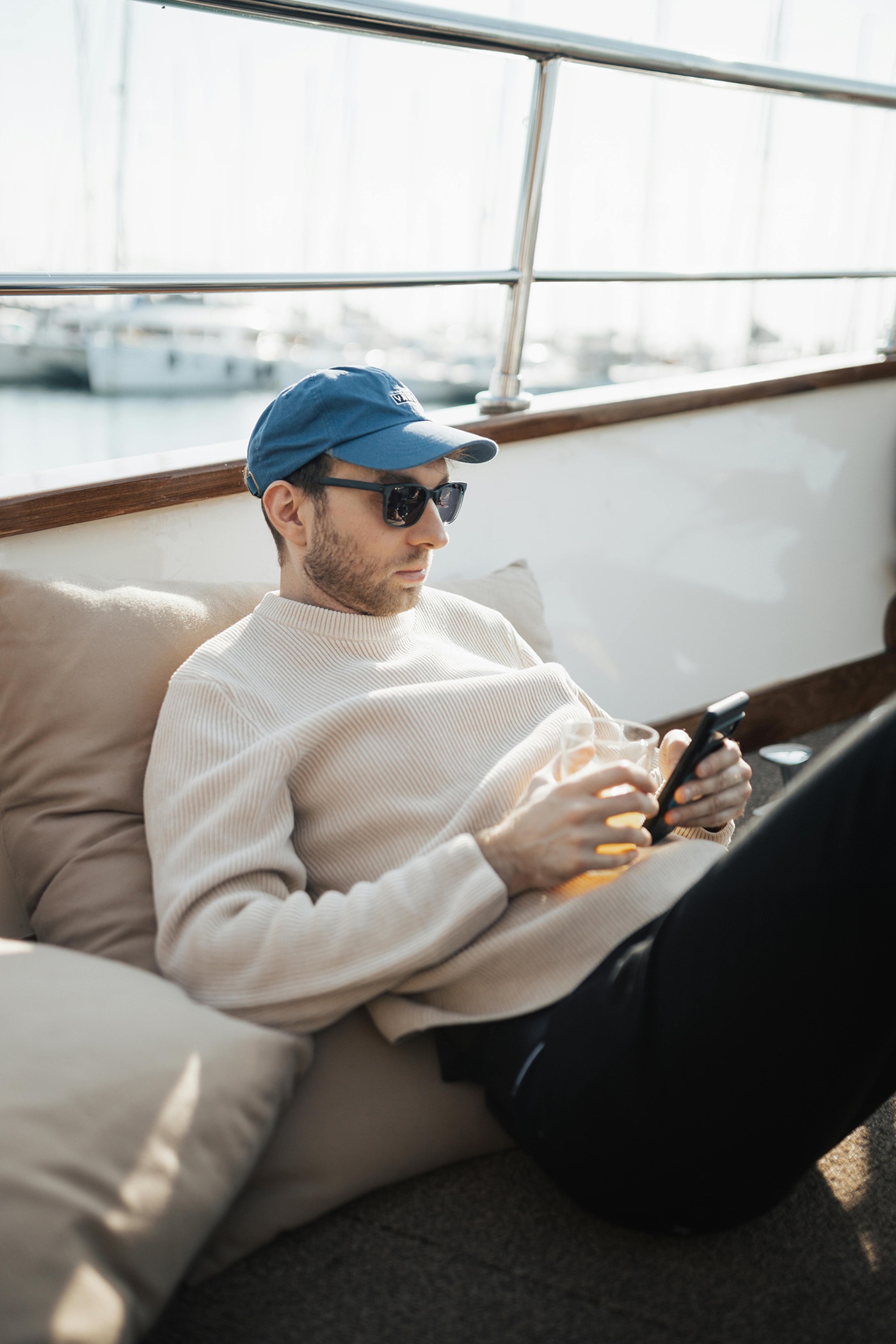 Un hombre revisando su teléfono mientras toma un trago en el lounge de su yate