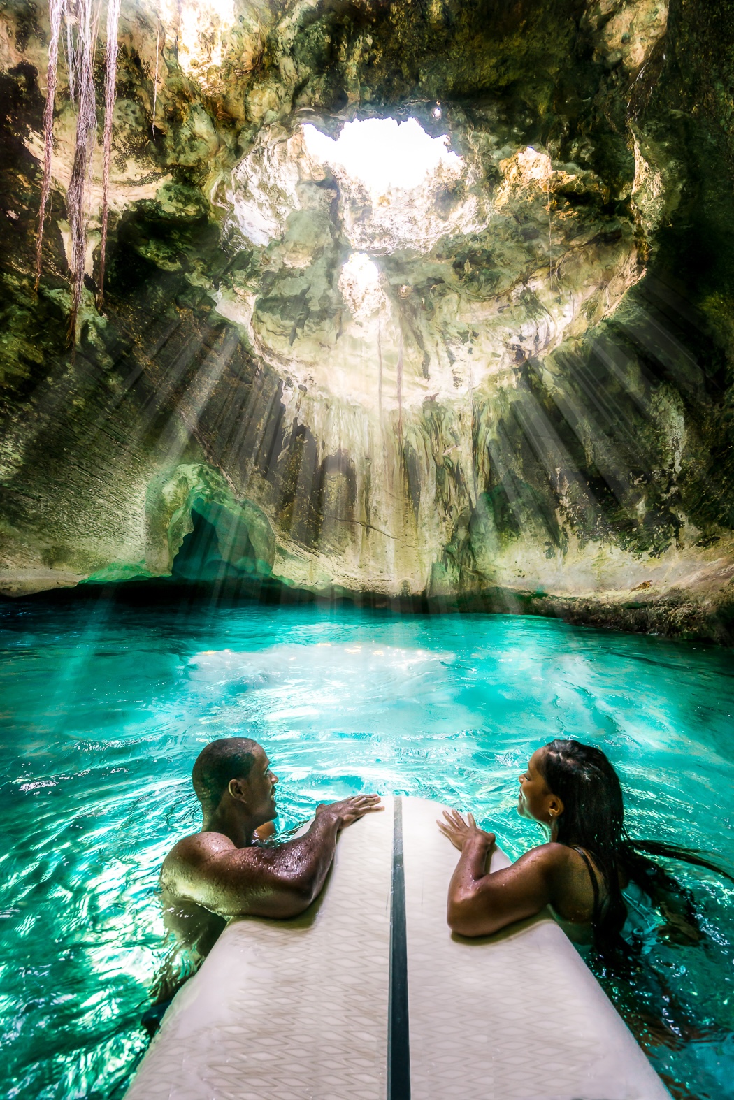 Two figures inside a sea grotto with light entering from above through a roof opening