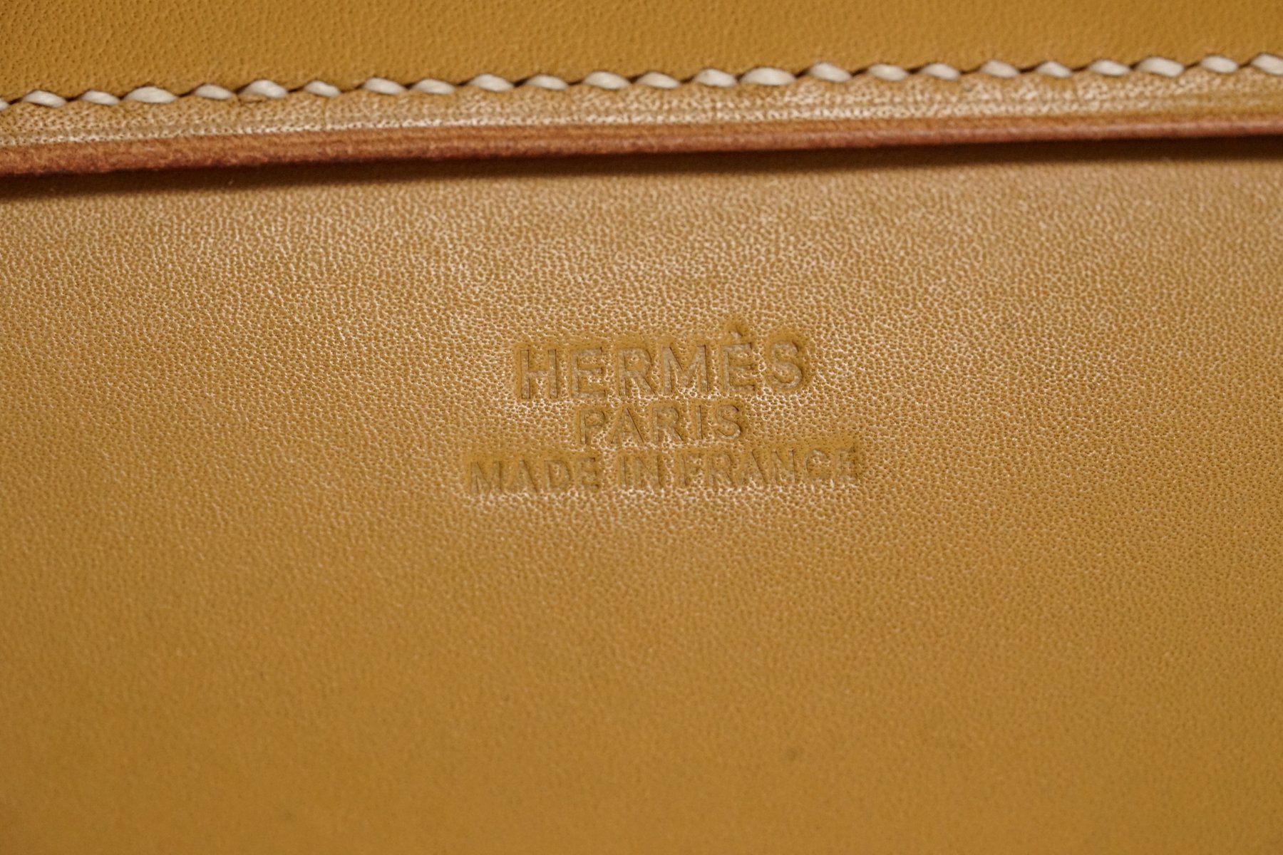 Close detail of the Hermès name recessed into the leather of the Pippa armchair.