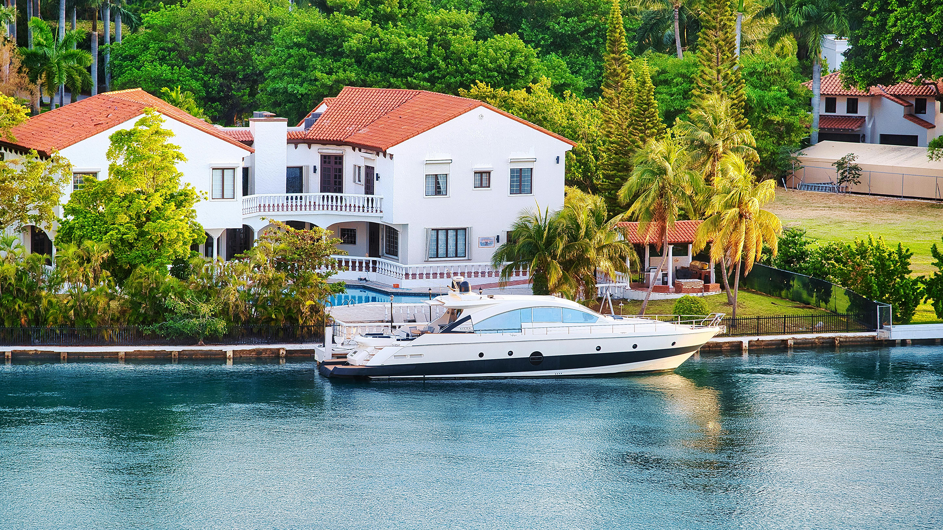Aerial view of a waterfront residence with yacht moored at private dock