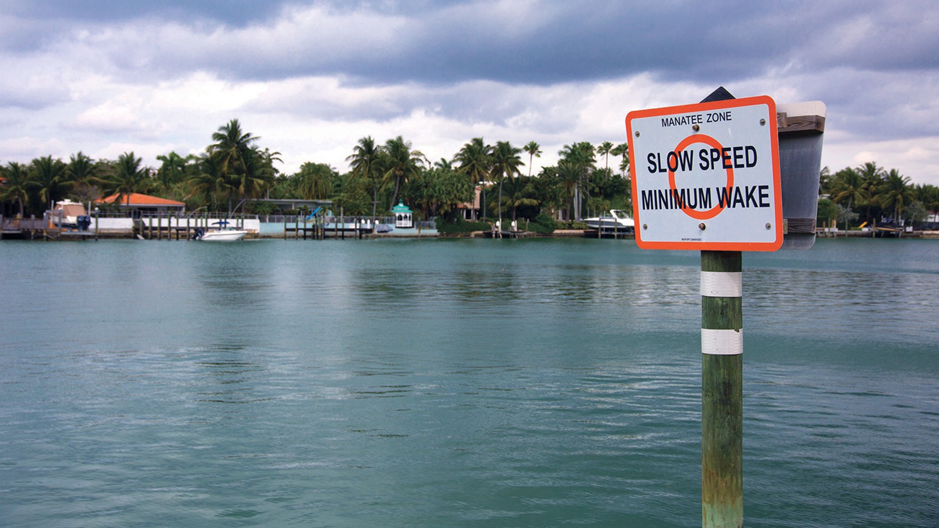 A regulatory sign in the water reading Slow Speed Minimum Wake