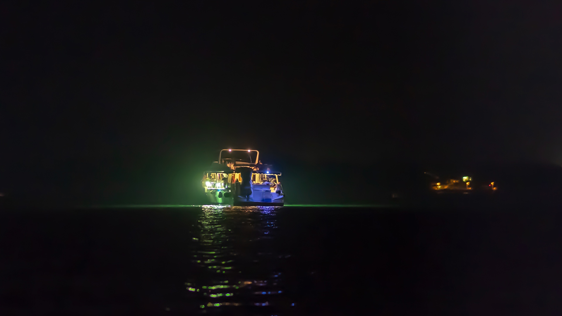 Vista desde la popa de un barco adentrándose en el océano de noche
