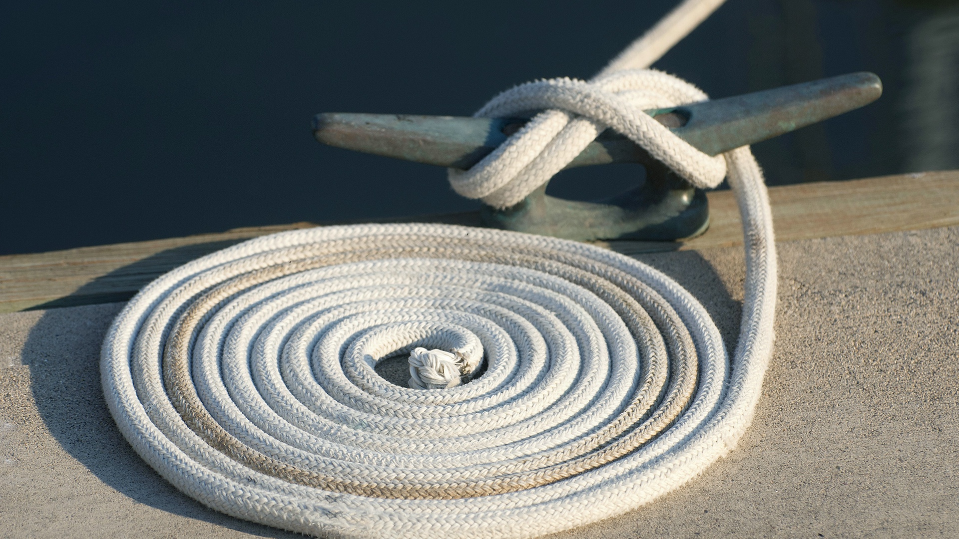 A dock line properly coiled and secured on a cleat at a marina