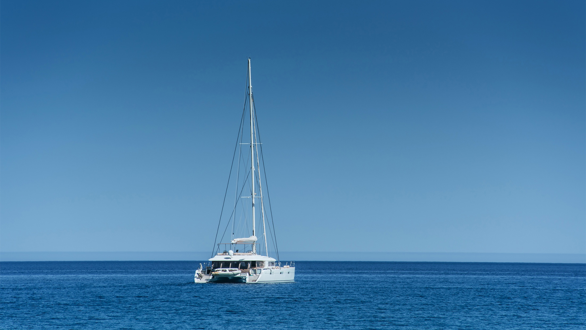 A white catamaran at anchor in deep blue water off Eleuthera