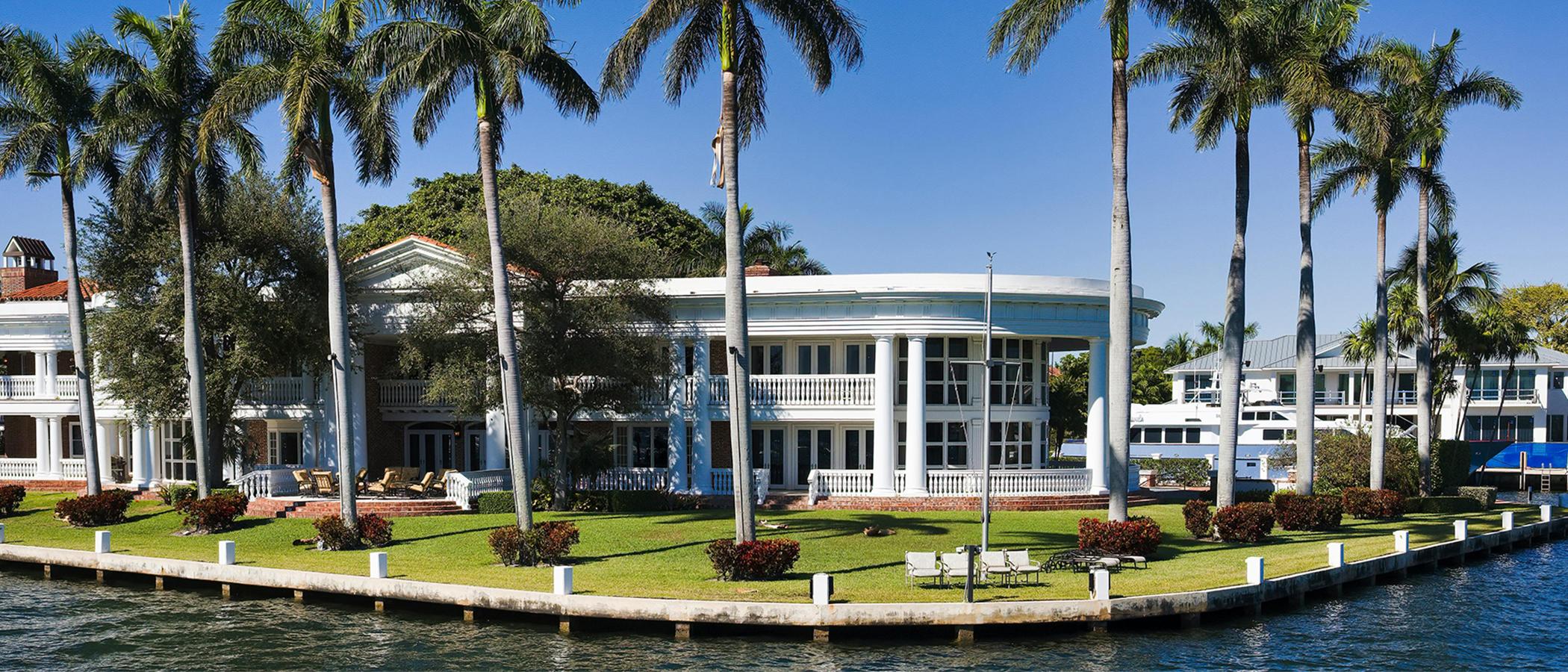 Classic American-style waterfront home seen from the water in a panoramic composition