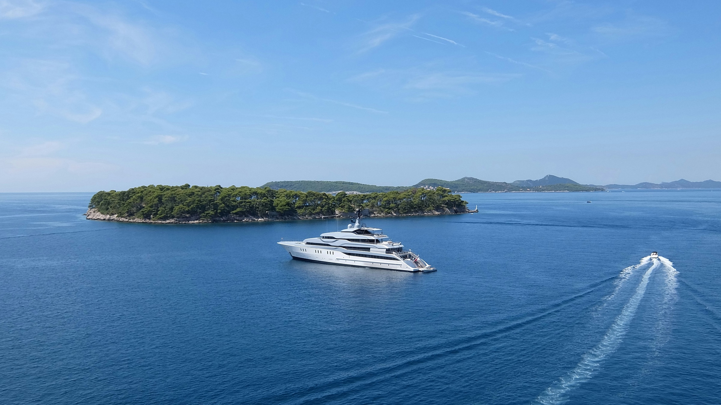 Aerial view of a private island with a superyacht at anchor