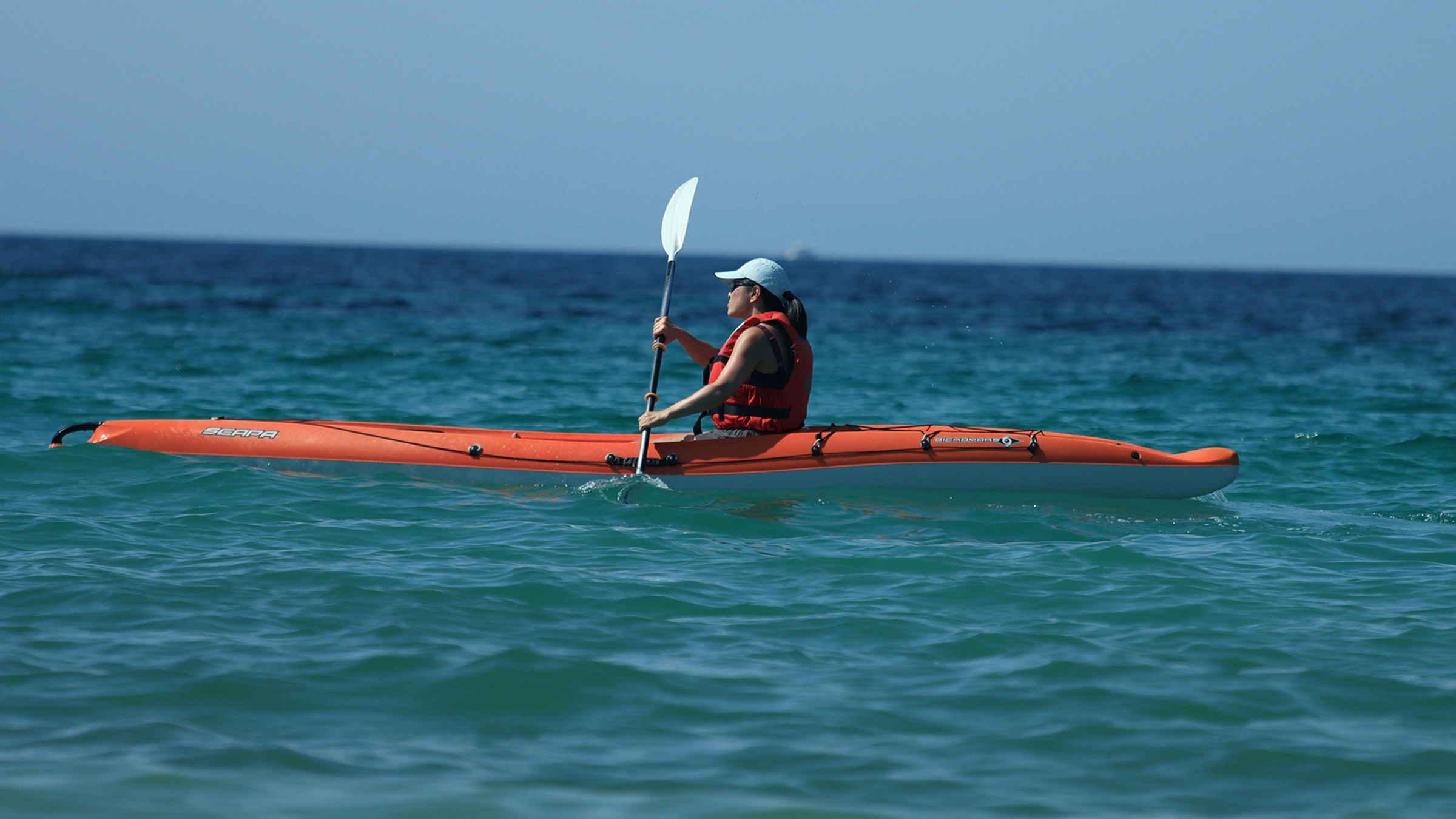 A woman paddling a kayak on open water