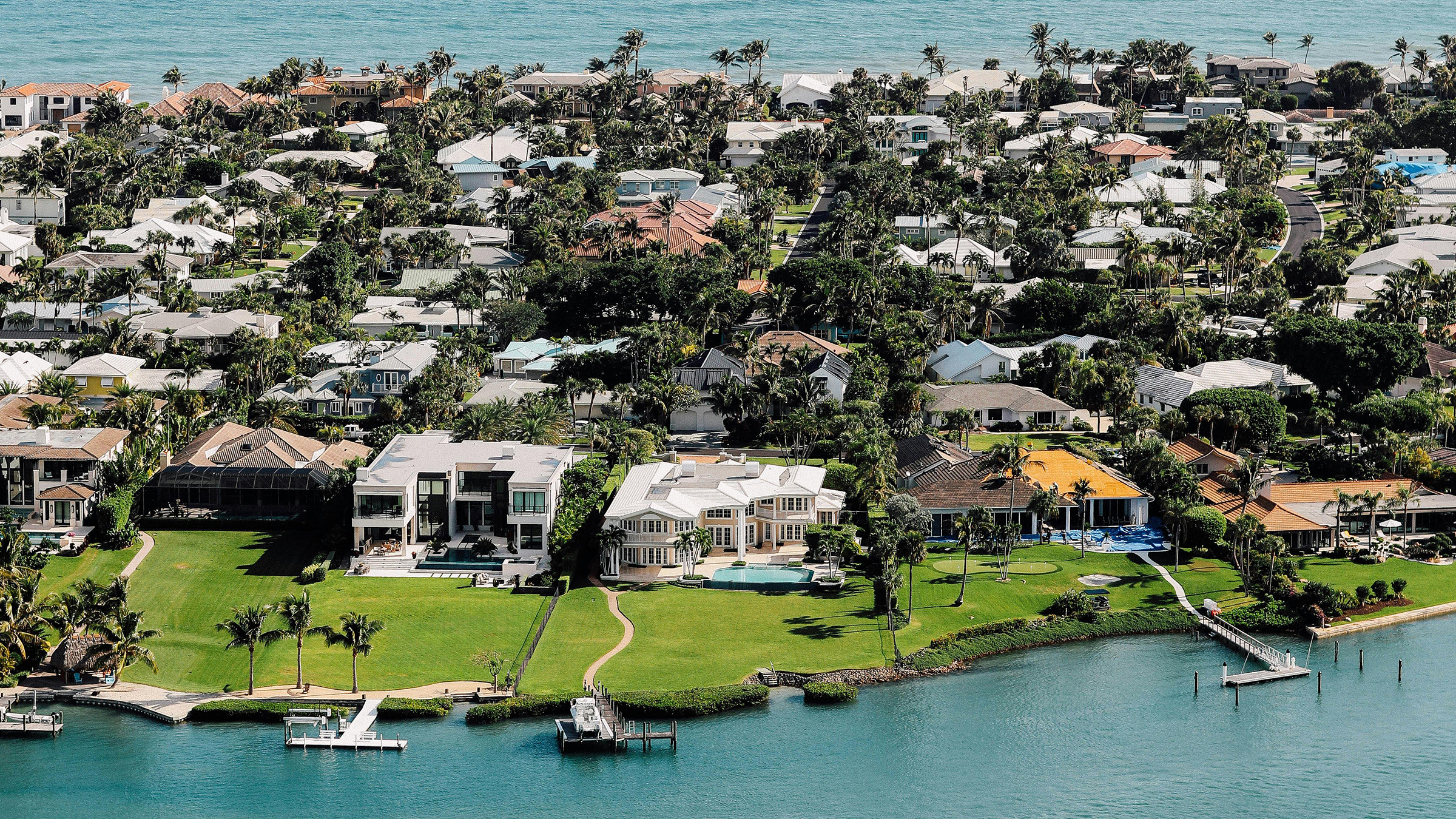 Aerial view of a coastline lined with waterfront homes and the ocean on the horizon