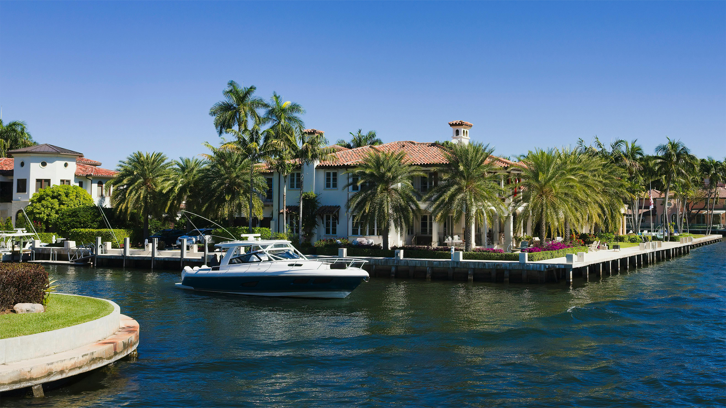 Corner-lot waterfront residence with yacht moored at the front dock