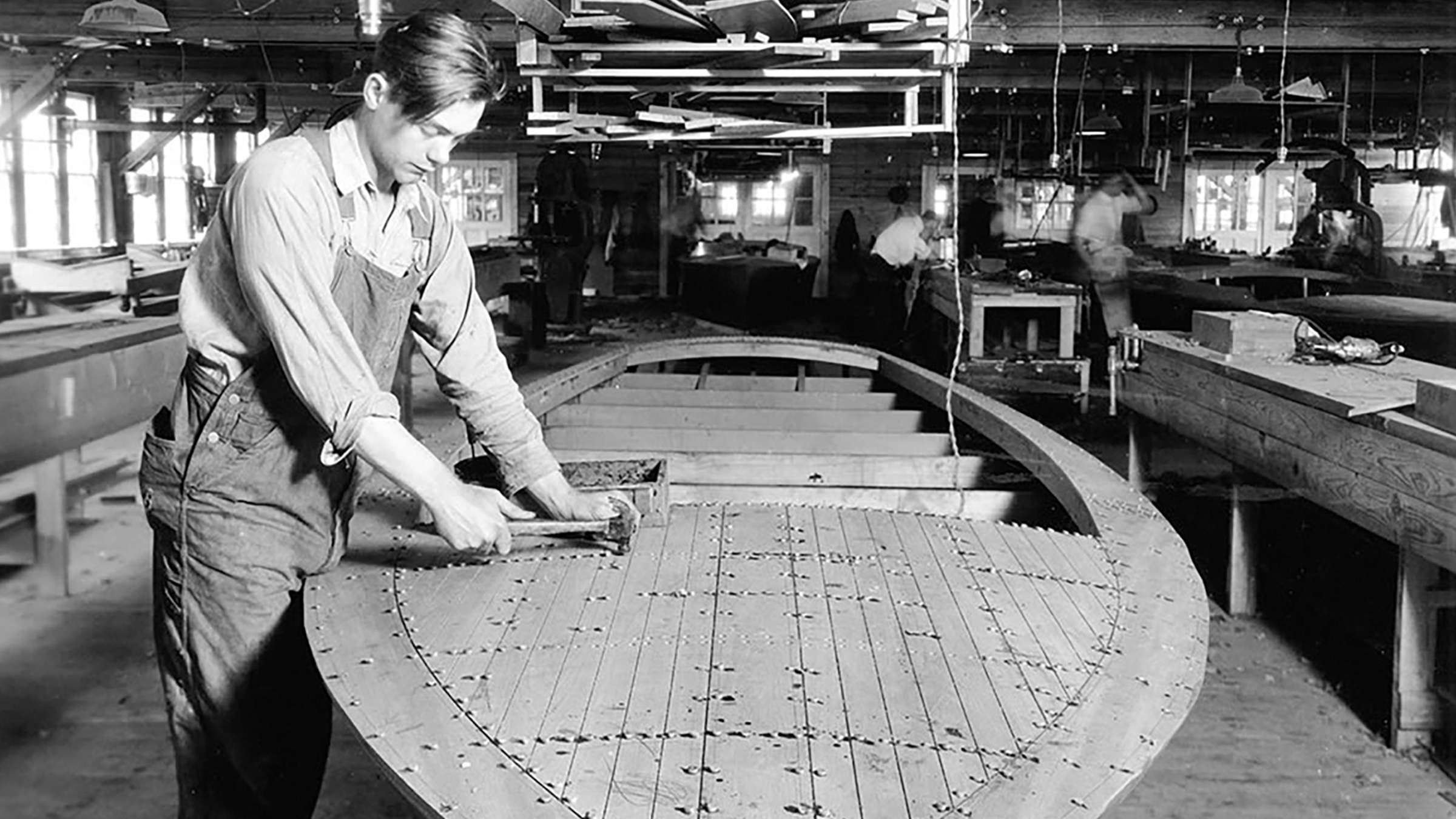 Un carpintero trabajando en el casco de una Chris-Craft en el astillero en 1948