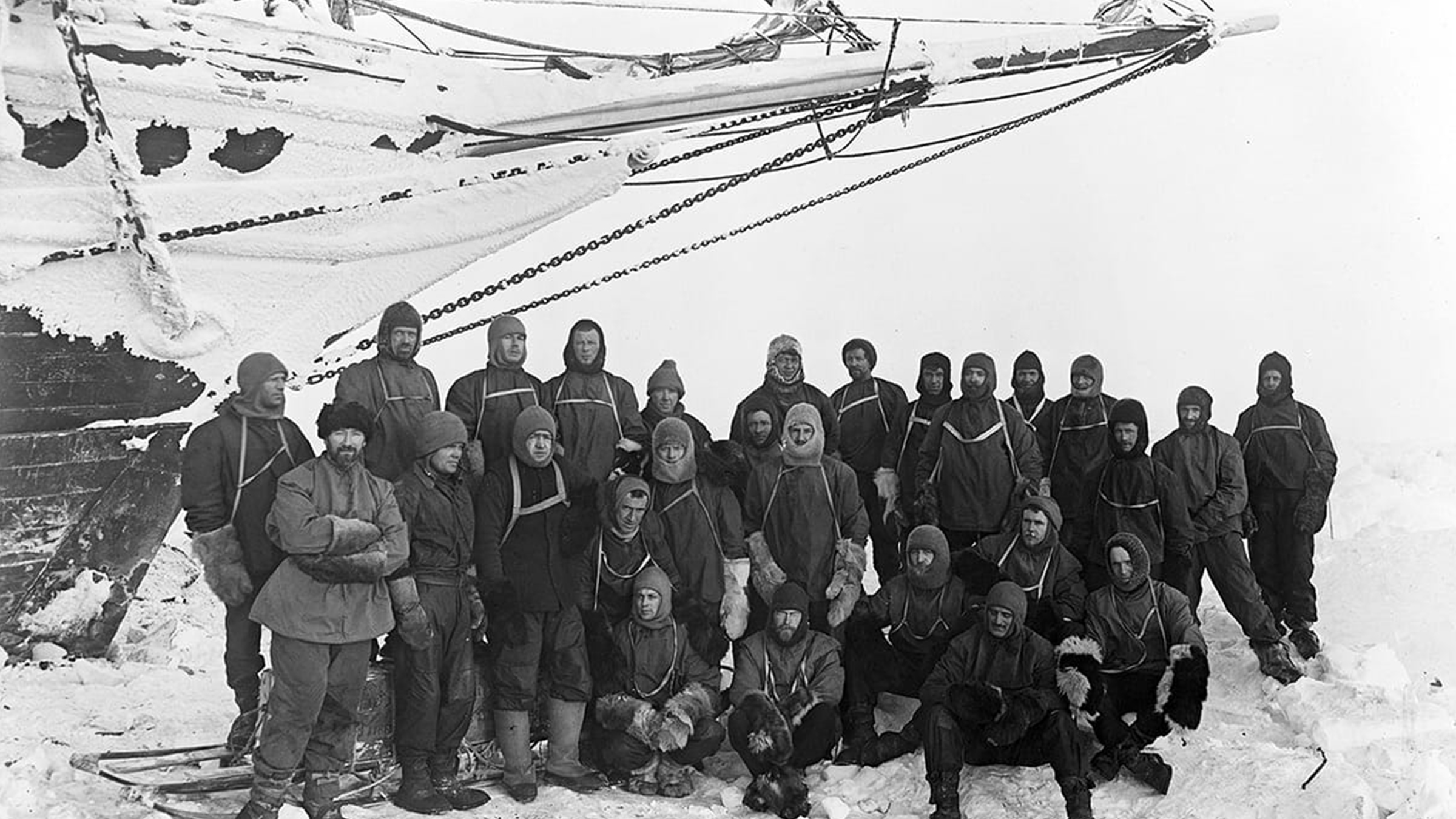 Tripulación del Endurance reunida con ropa polar completa bajo la proa del barco, fotografiada por Frank Hurley