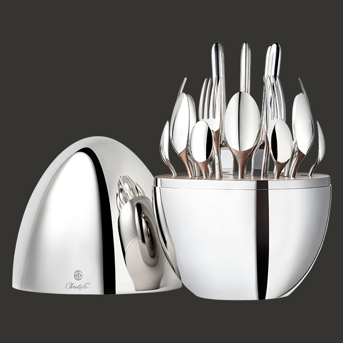 Mood egg open, the 24 pieces arranged radially in the walnut interior, photographed against deep grey.