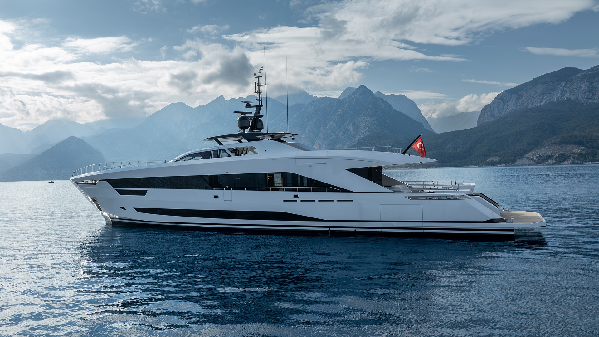 The Alia 43M at anchor with mountains in the background, in the Mediterranean