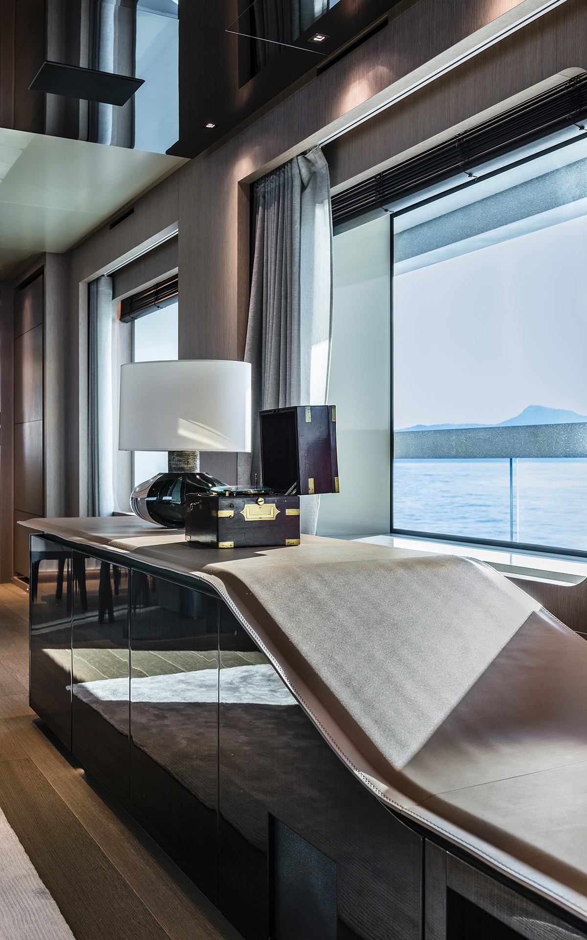 Yacht interior with a design cabinet beside a window showing sea and mountains