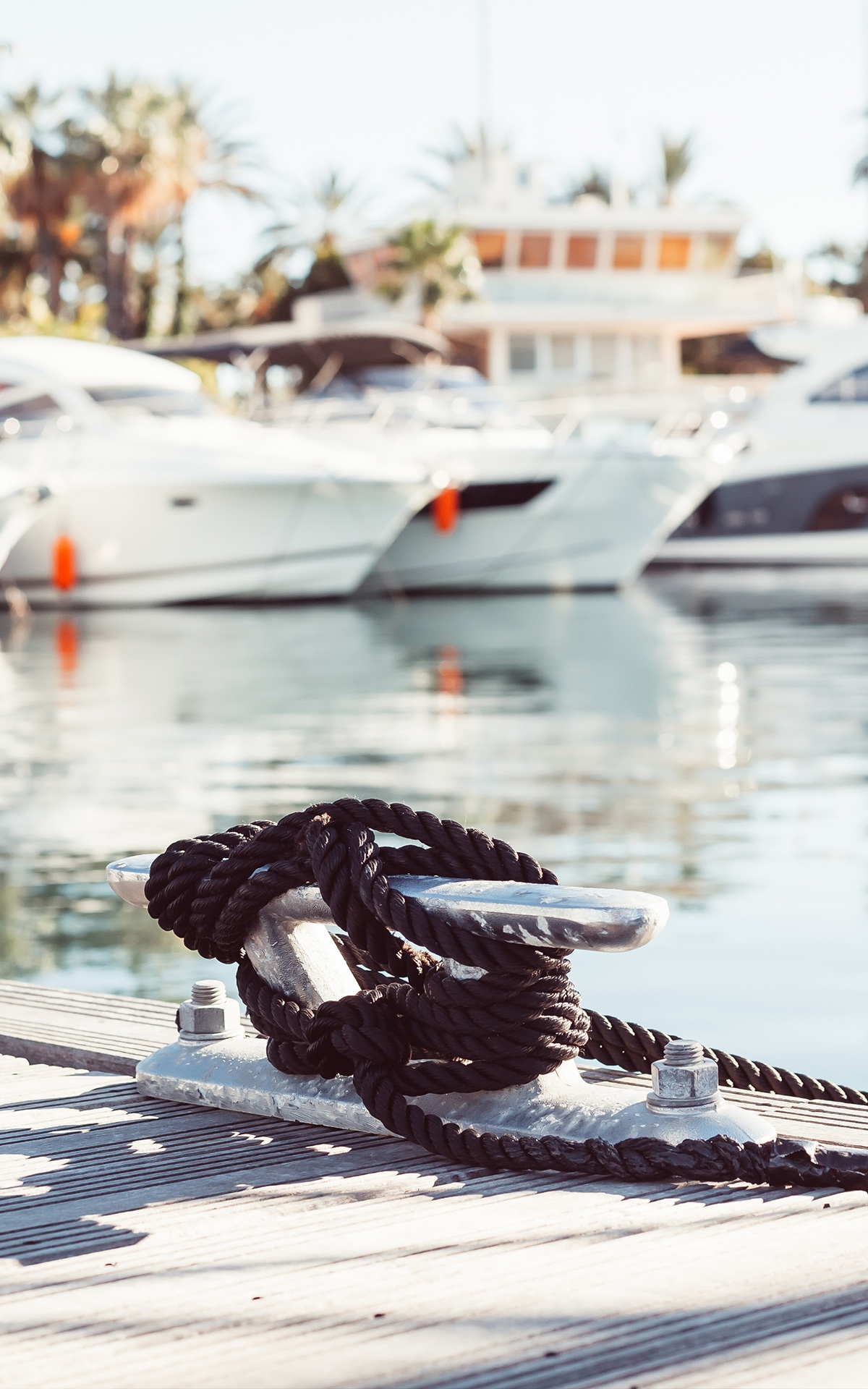 Close view of a dock cleat with boats behind in a marina