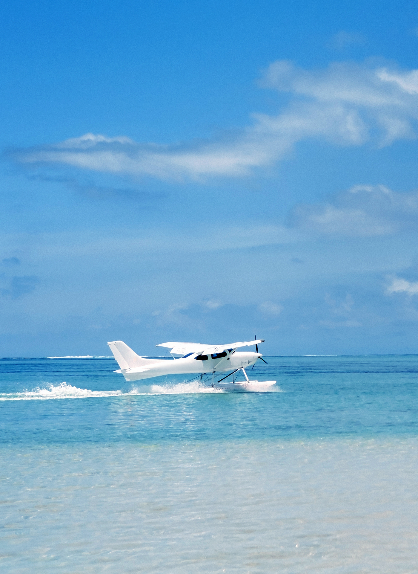 Hidroavión amerizando en aguas turquesas de las Bahamas, composición vertical