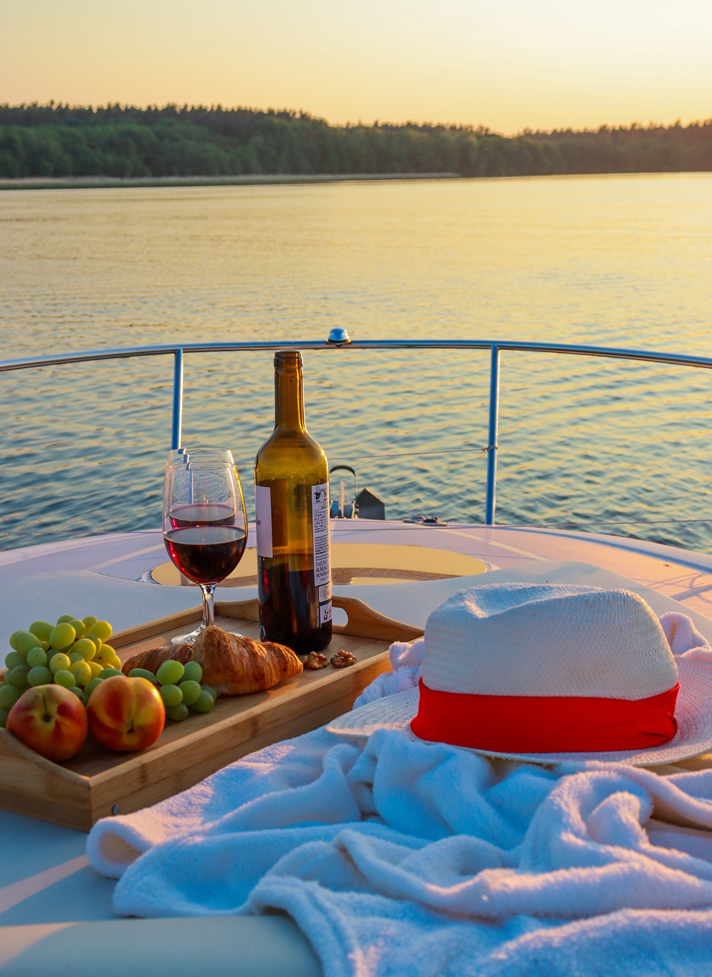 Wine, grapes and a croissant on deck at sunset