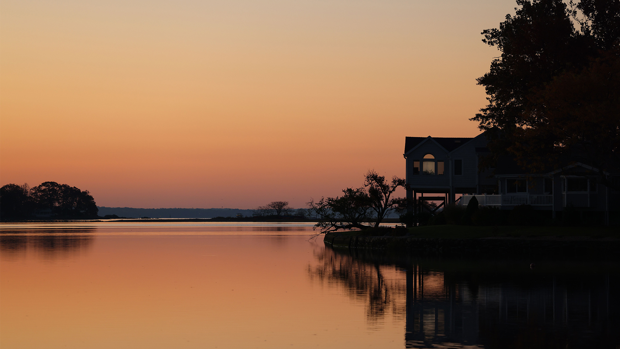 Waterfront home facing open water at sunset