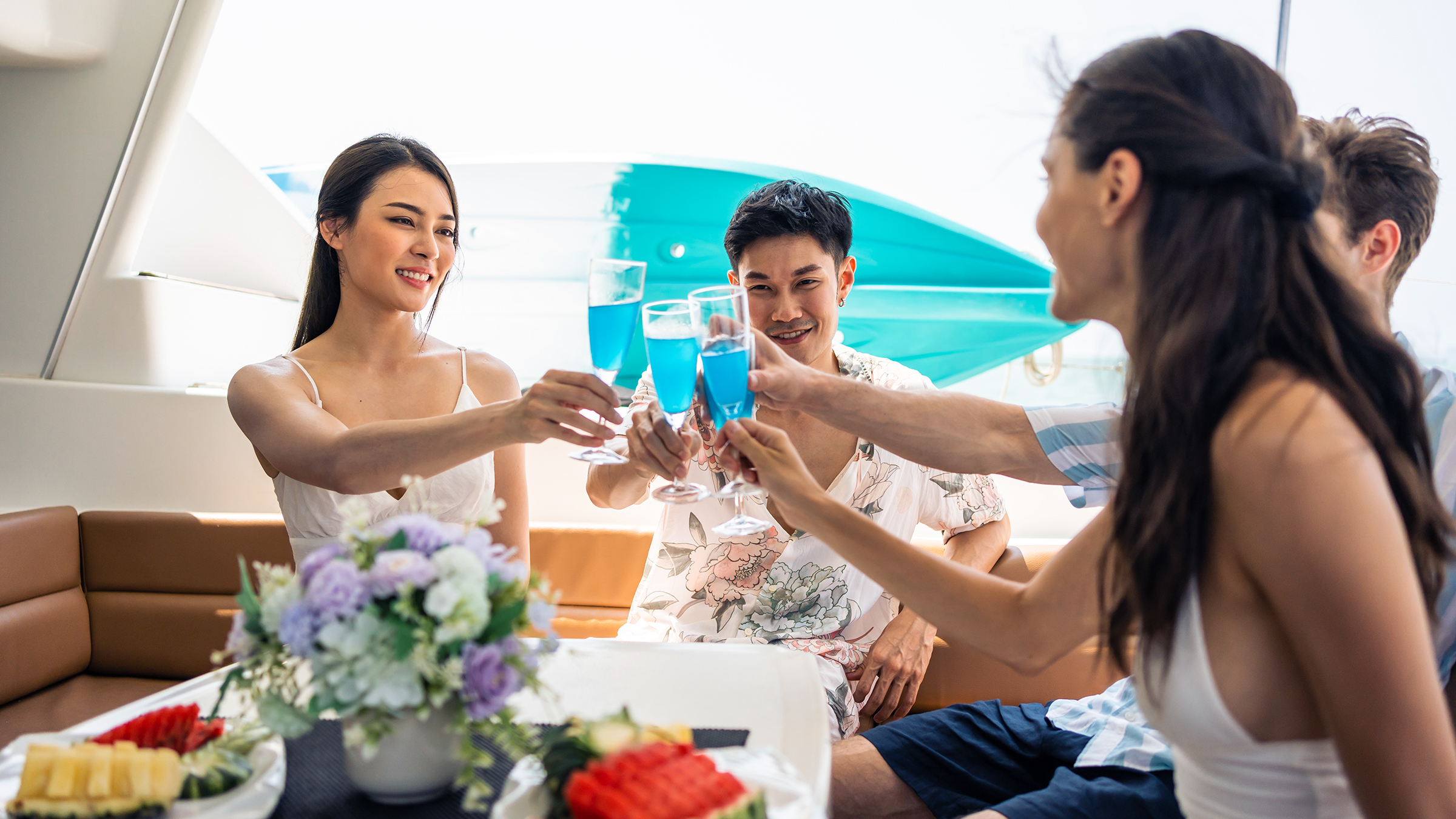 Dos parejas tomando champán con fruta en el cockpit de un yate