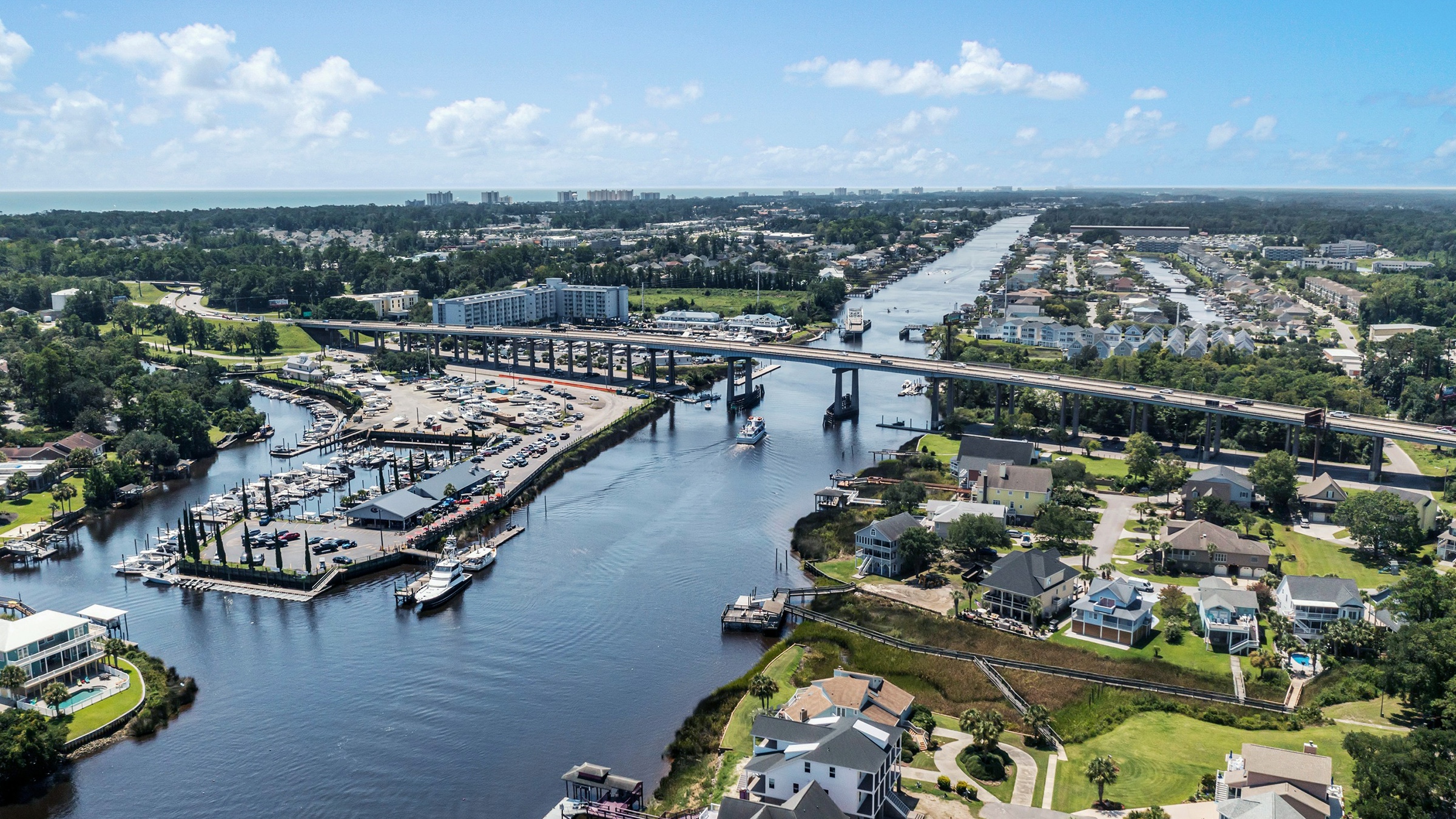 Aerial view of an Intracoastal channel with a marina along one bank and a bridge beyond