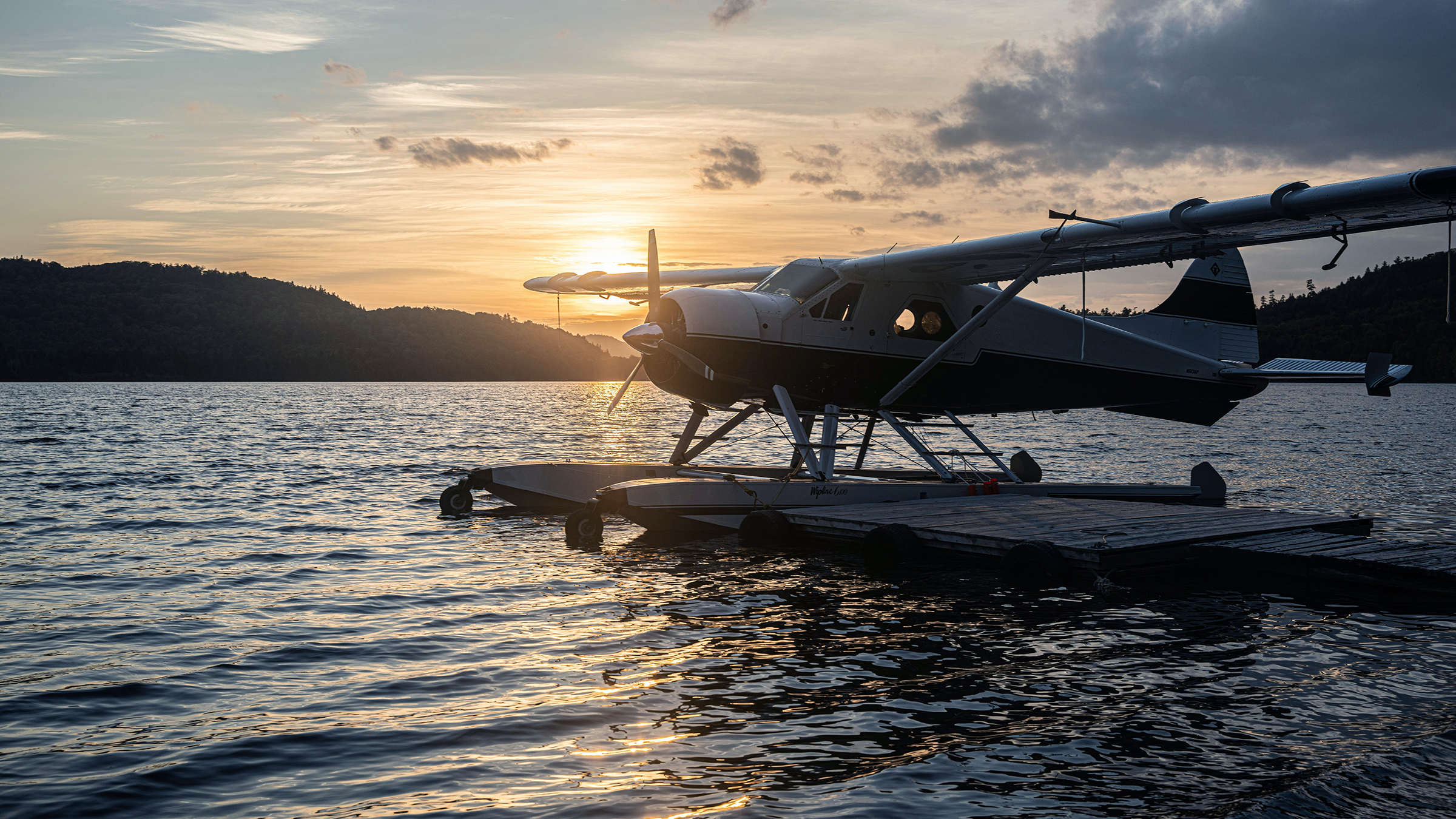 Hidroavión amarrado a un muelle, a contraluz al atardecer