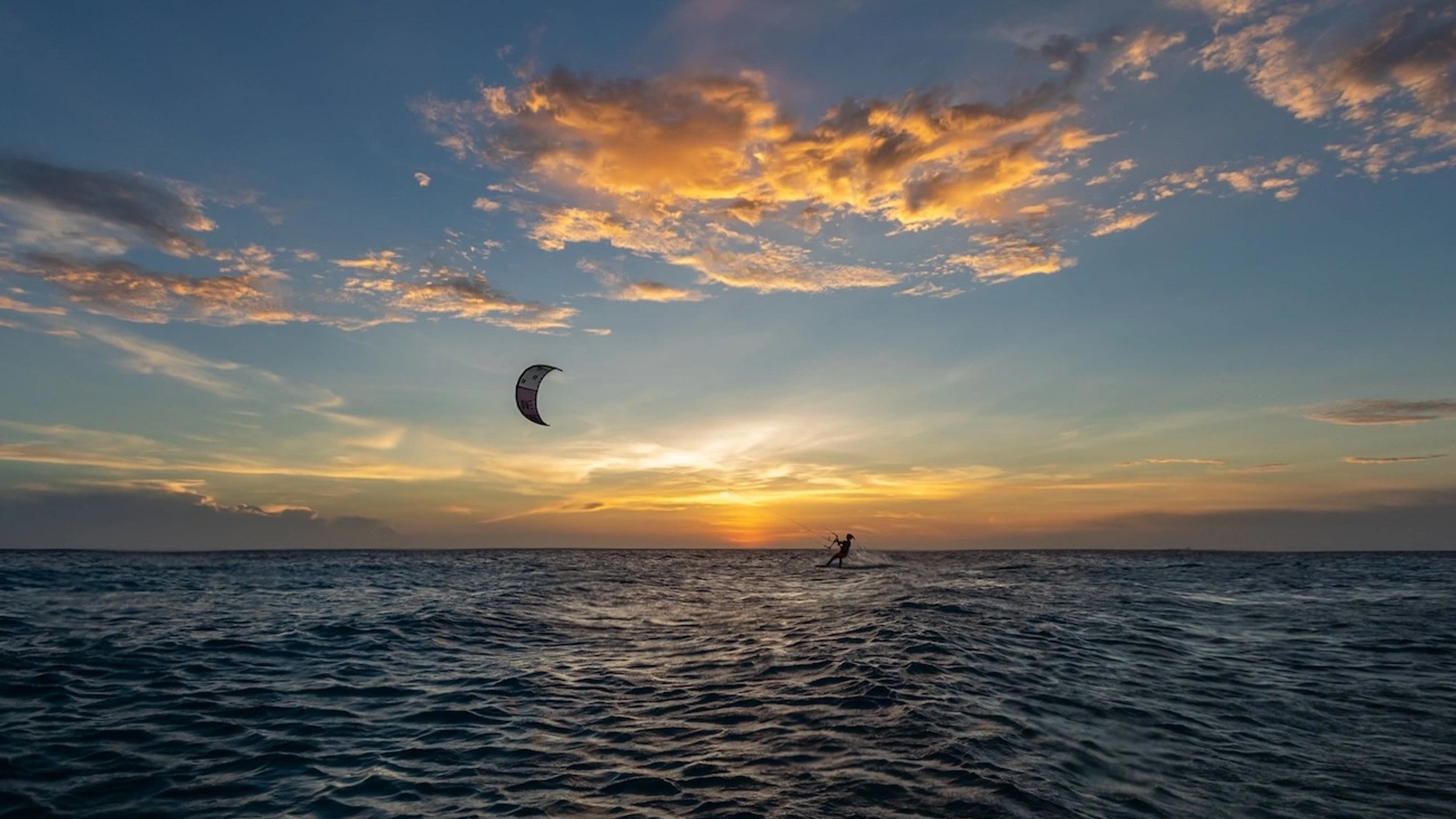 A kitesurfer riding into a sunset