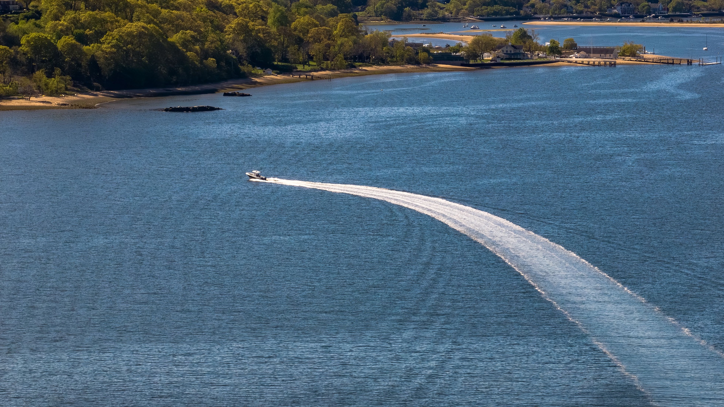 Aerial view over calm lake water with a distant powerboat