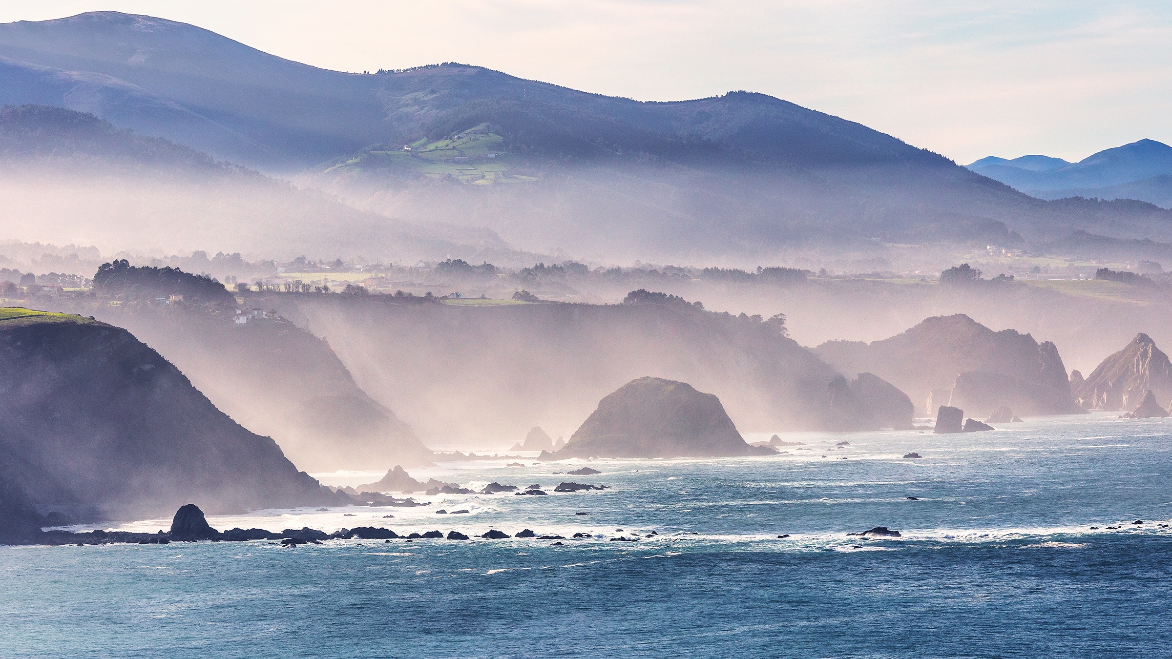 Bright blue Pacific water under a bank of fog
