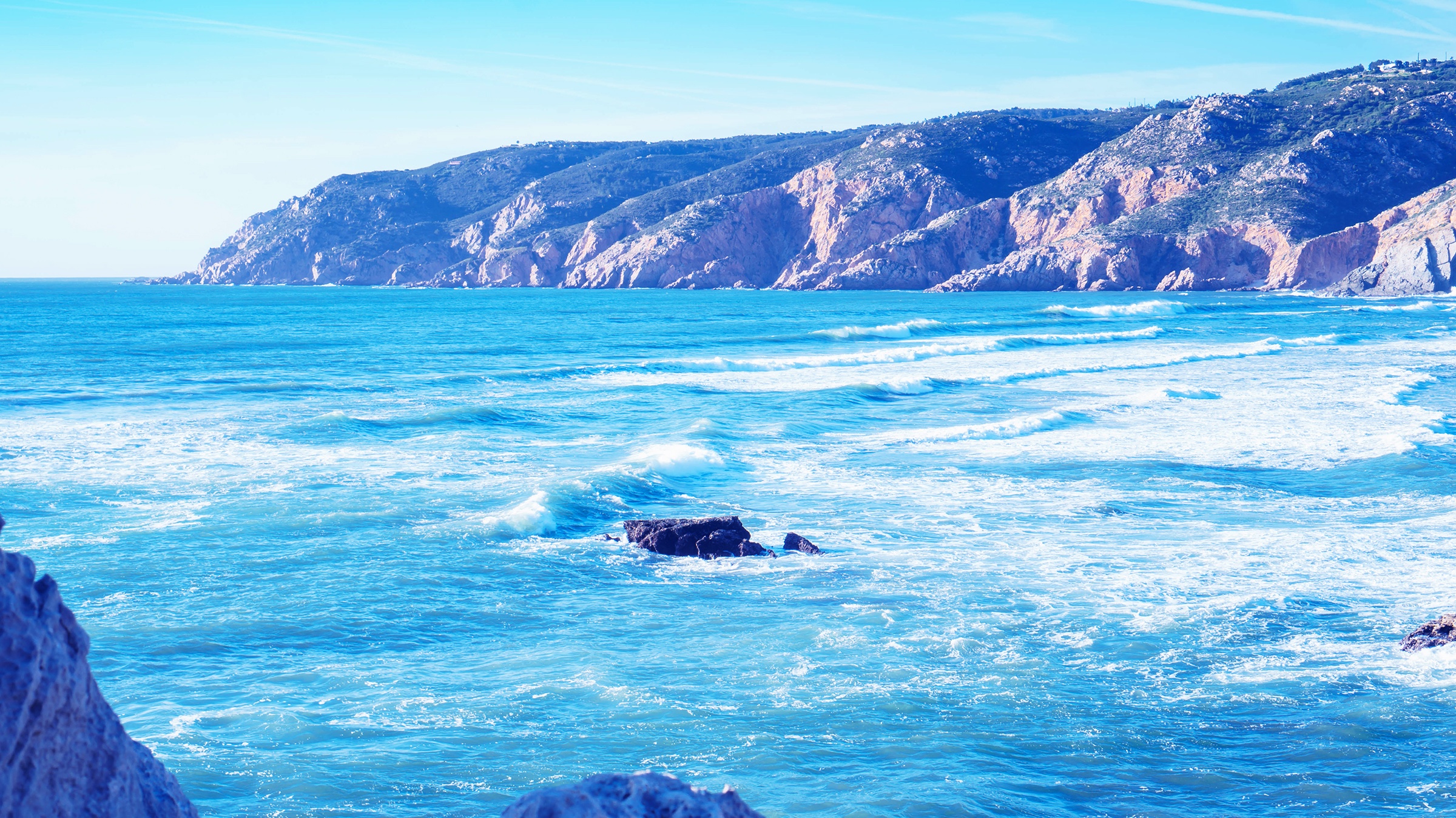A blue lagoon and rocky ravine with foamy waves
