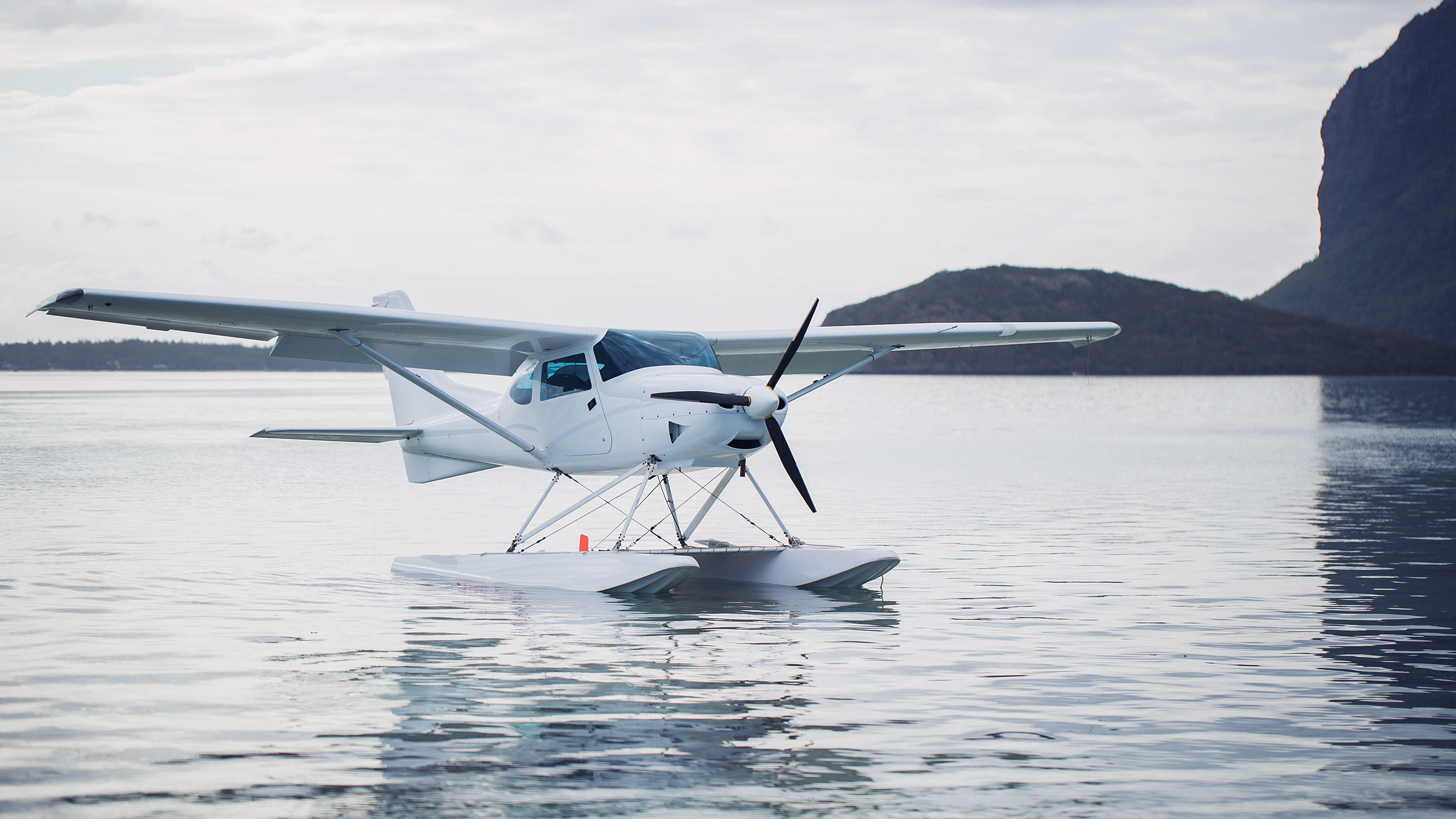 Hidroavión bajo sobre el agua cerca de una costa montañosa