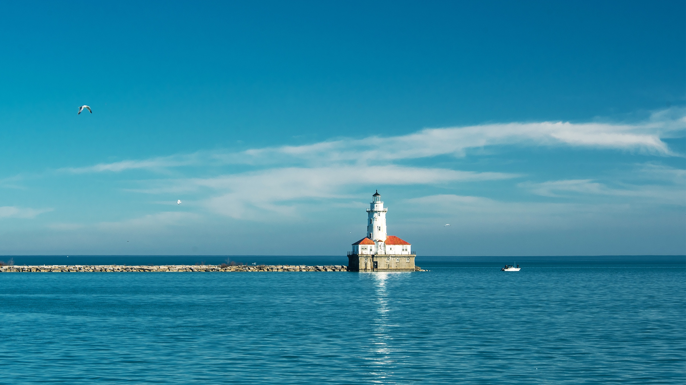 White lighthouse on a Michigan lake with a boat passing