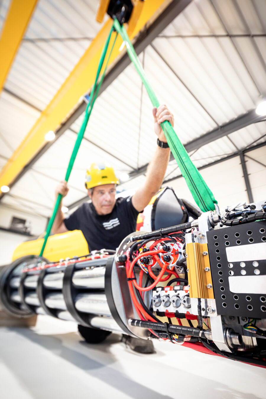 An engineer guides a component toward a submersible under construction