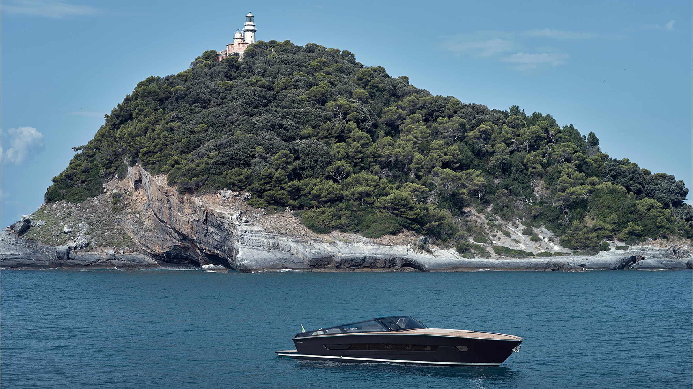 Itama 54 de perfil con un castillo sobre la cumbre de la costa al fondo