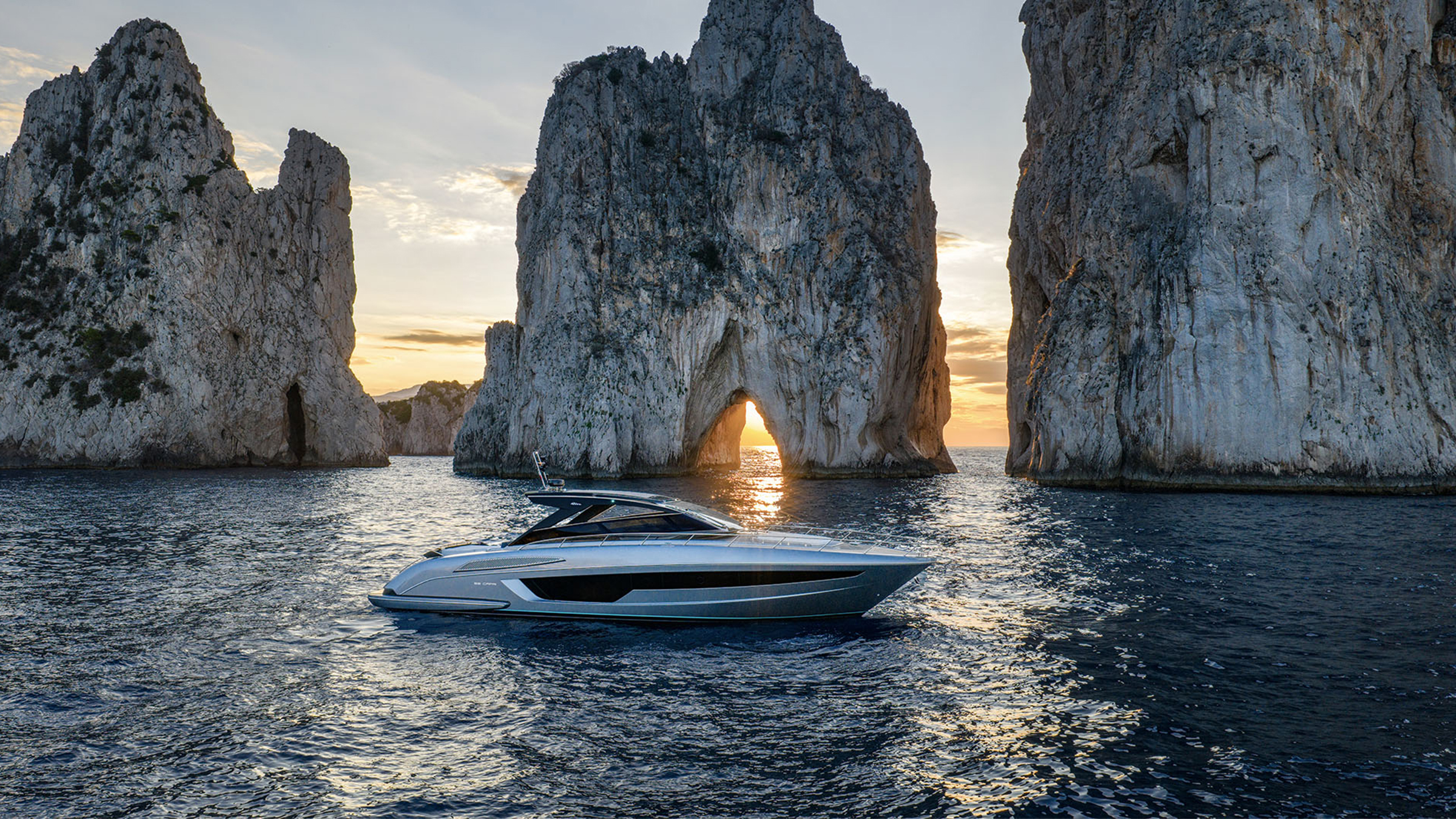 Riva 58 Capri fondeado ante formaciones rocosas costeras al atardecer