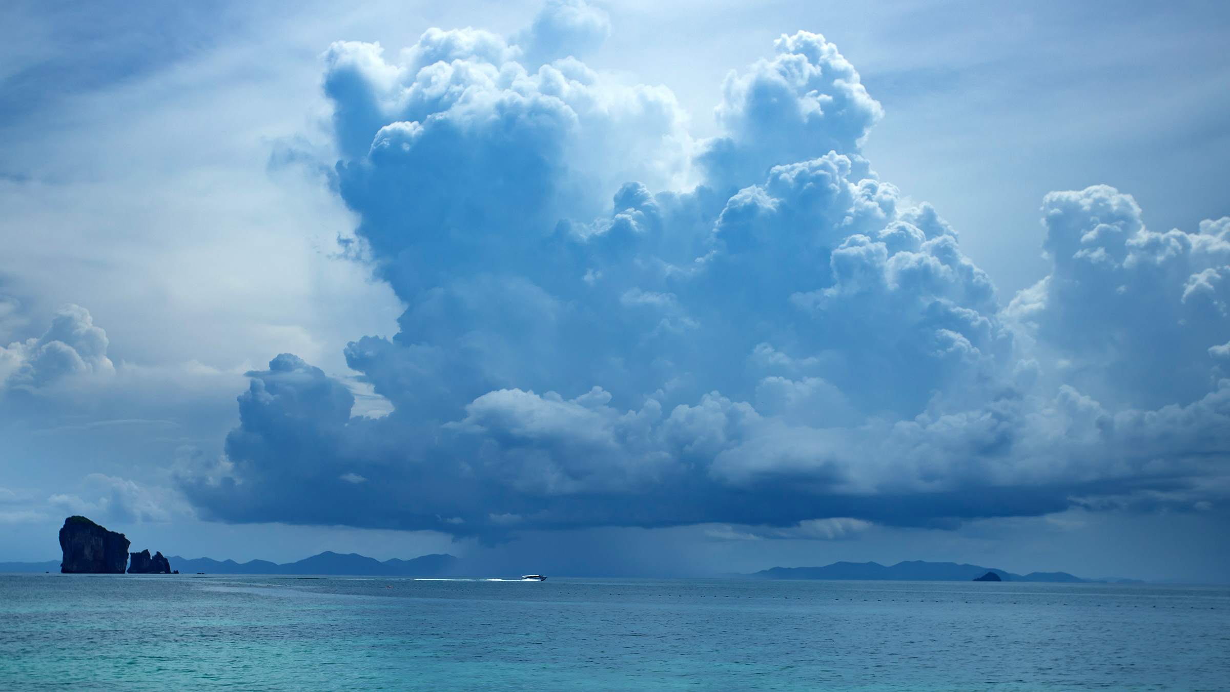Mar en calma con un barco a lo lejos y nubes de lluvia amenazantes