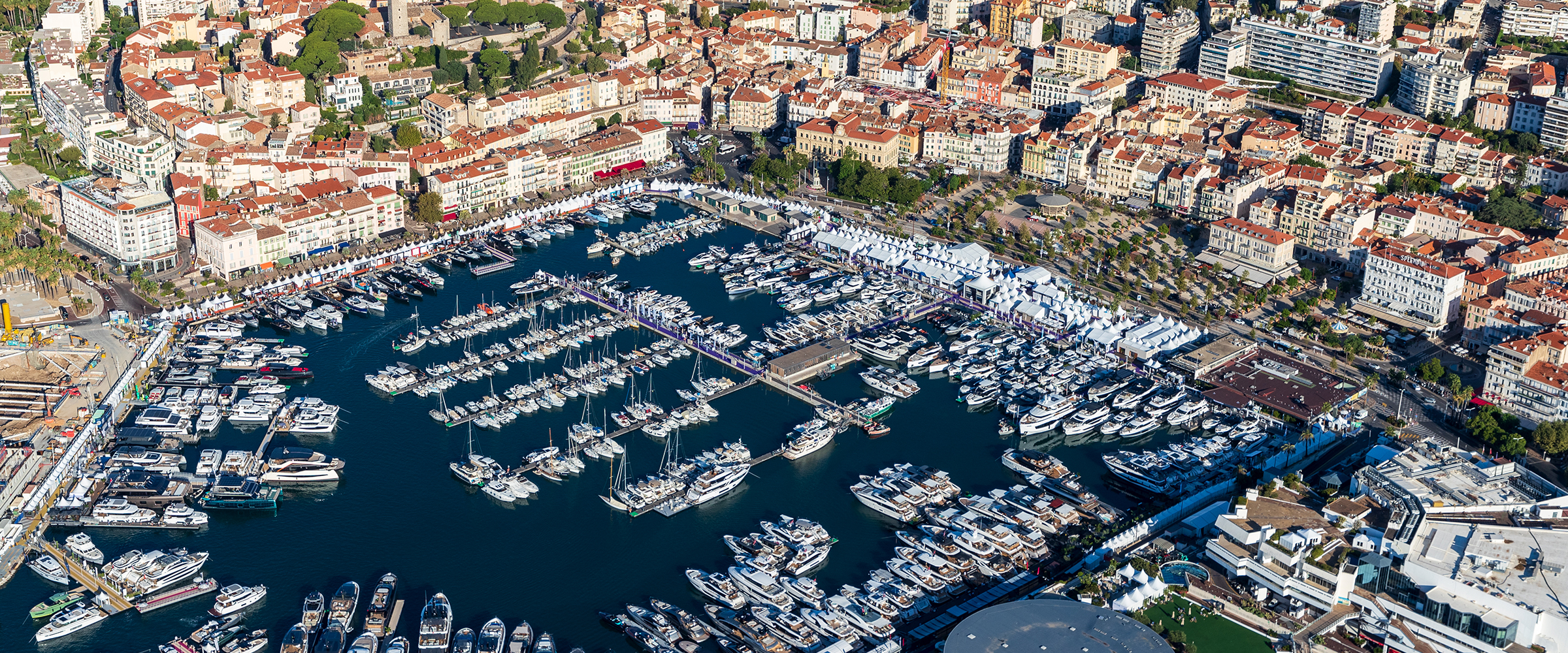 Vista aérea del Vieux Port de Cannes repleto de barcos en exposición, con la ciudad detrás