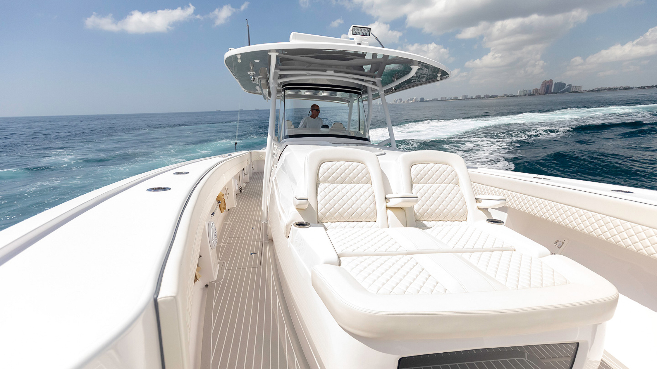 White padded seat facing the center console of a boat running near the coast