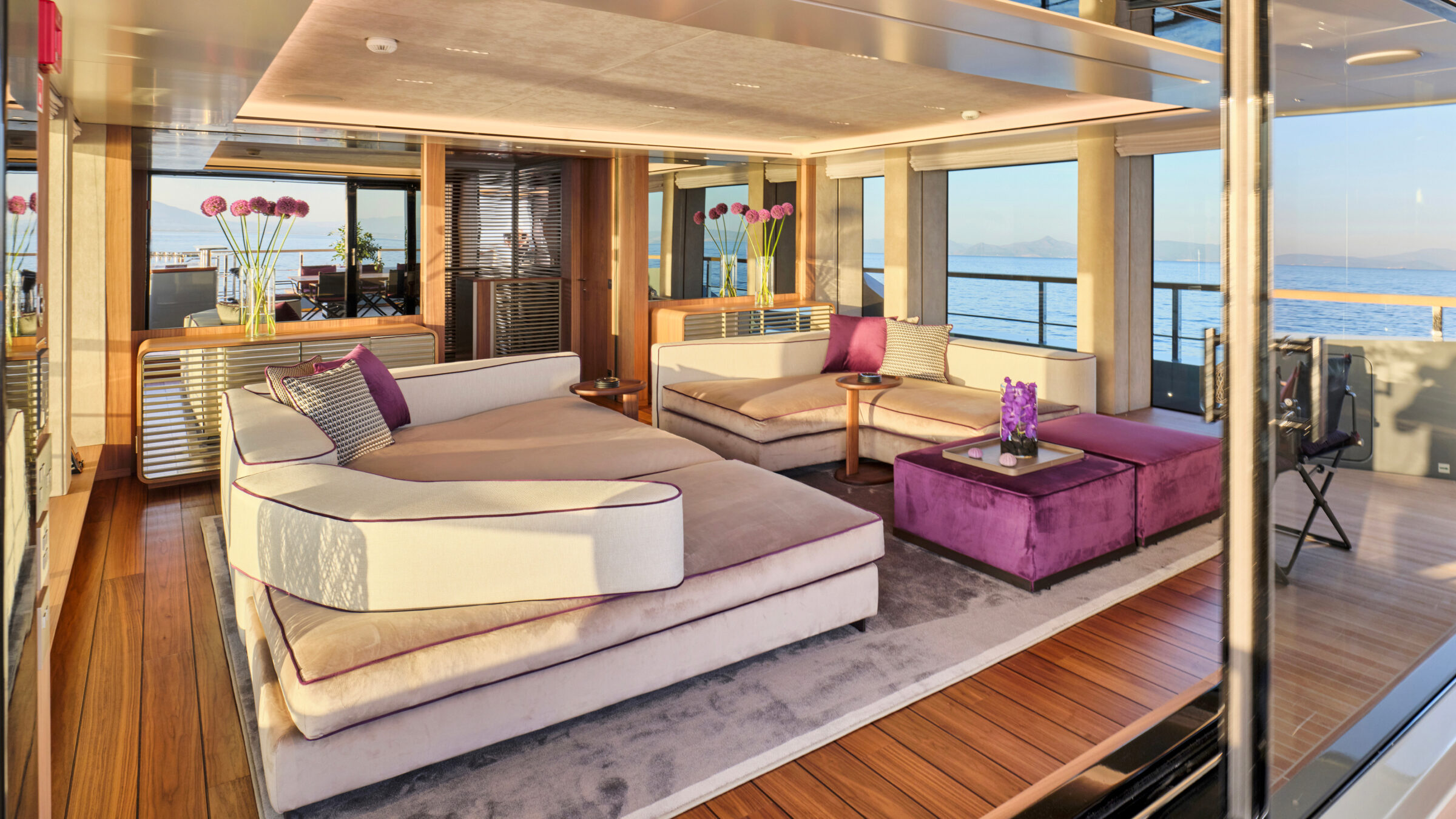 Superyacht salon with light sofas, purple accents and large windows to the sea