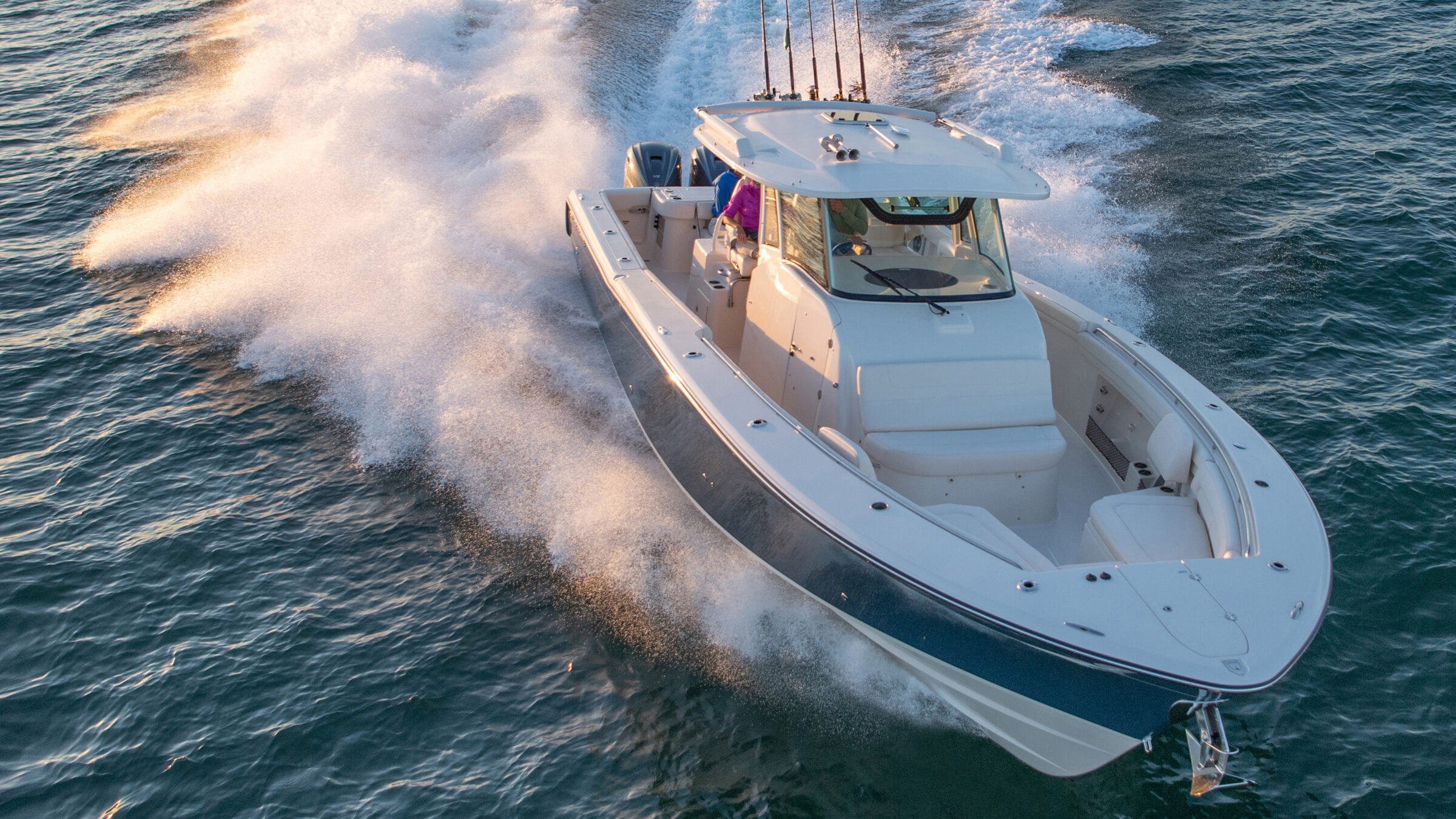 Center console boat running at speed at sunset, throwing up spray