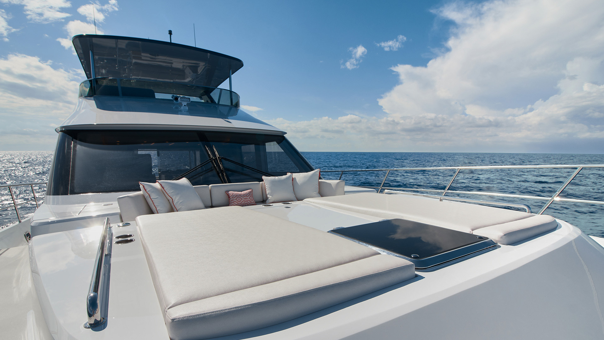 Foredeck sunpad of a yacht with cushions, facing the sea