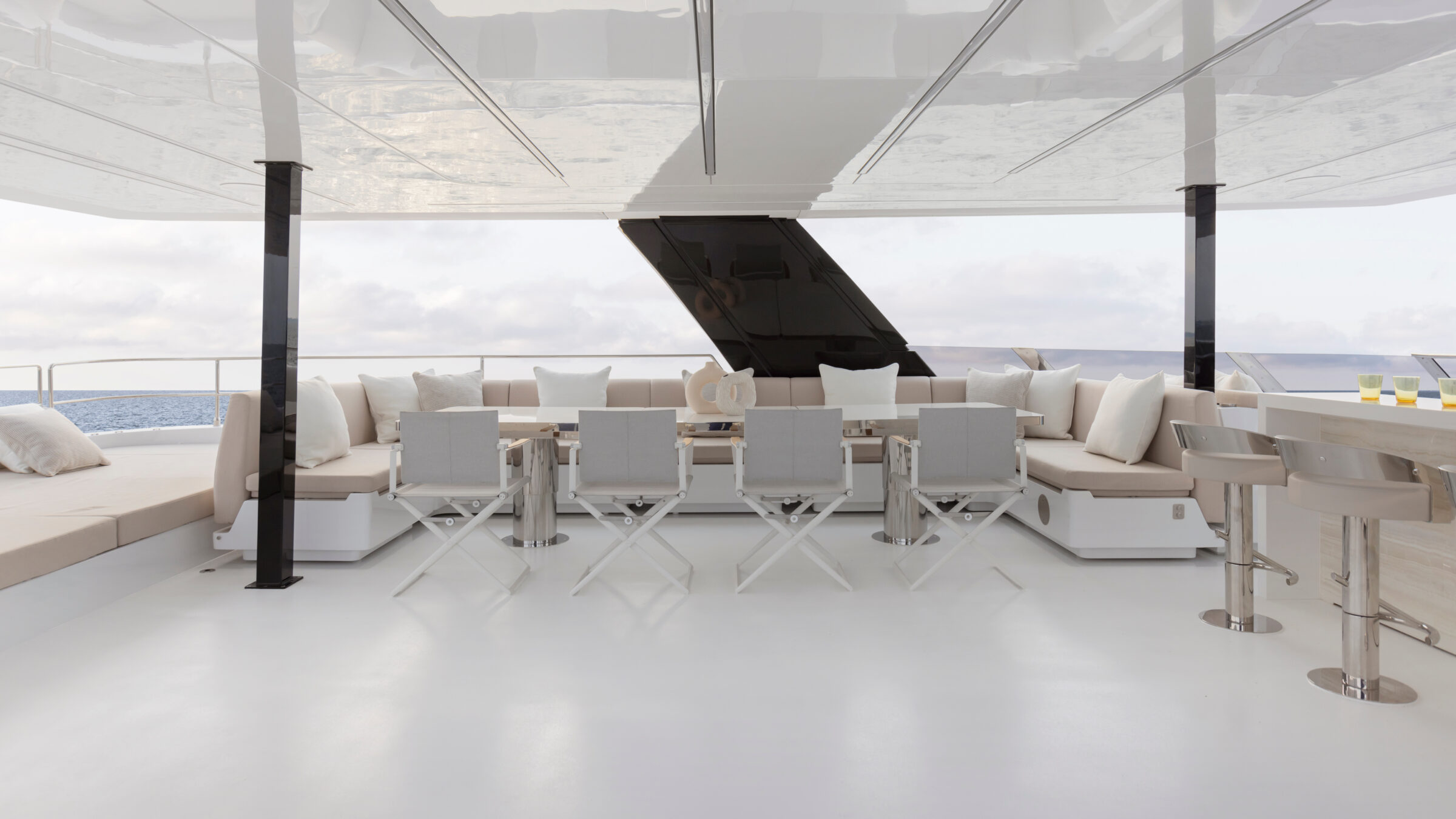 Outdoor dining on the flybridge of the 80 Sunreef Power Eco, with U-shaped sofa, chairs and bar