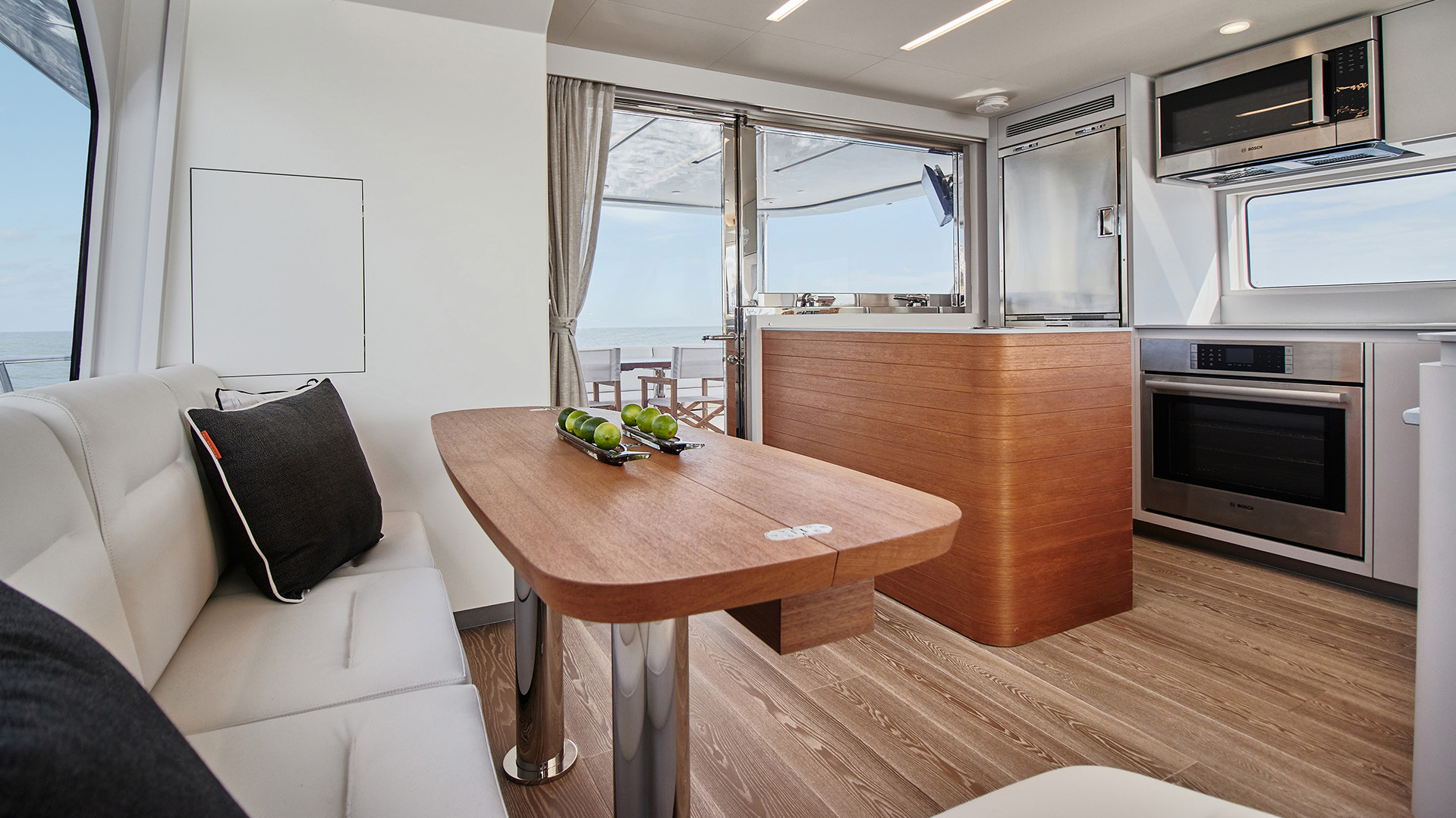 Interior dining area and galley of a yacht with a wood table and access to the stern