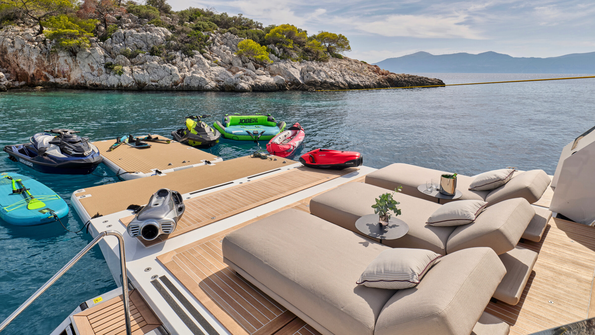 Superyacht swim platform with sun loungers and water toys in a cove