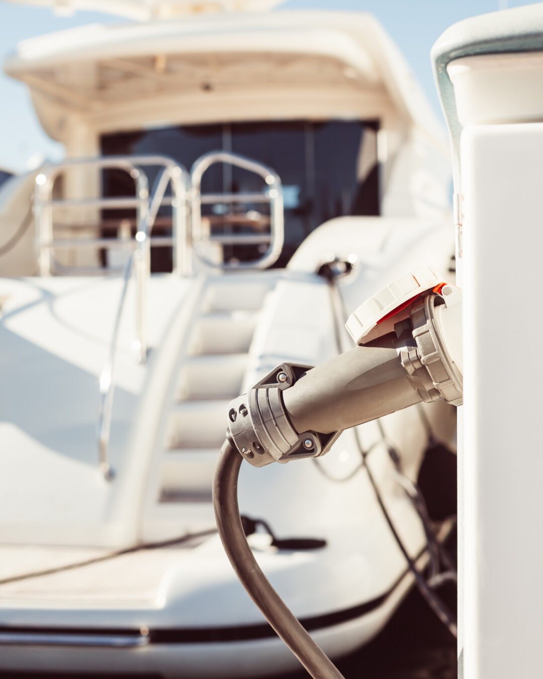 Electric charging connector on a dock, with a moored yacht in the background