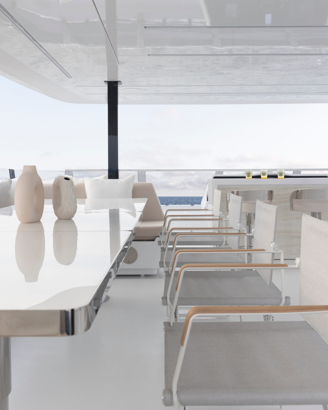Detail of the outdoor dining area on the flybridge, with chairs around a white table