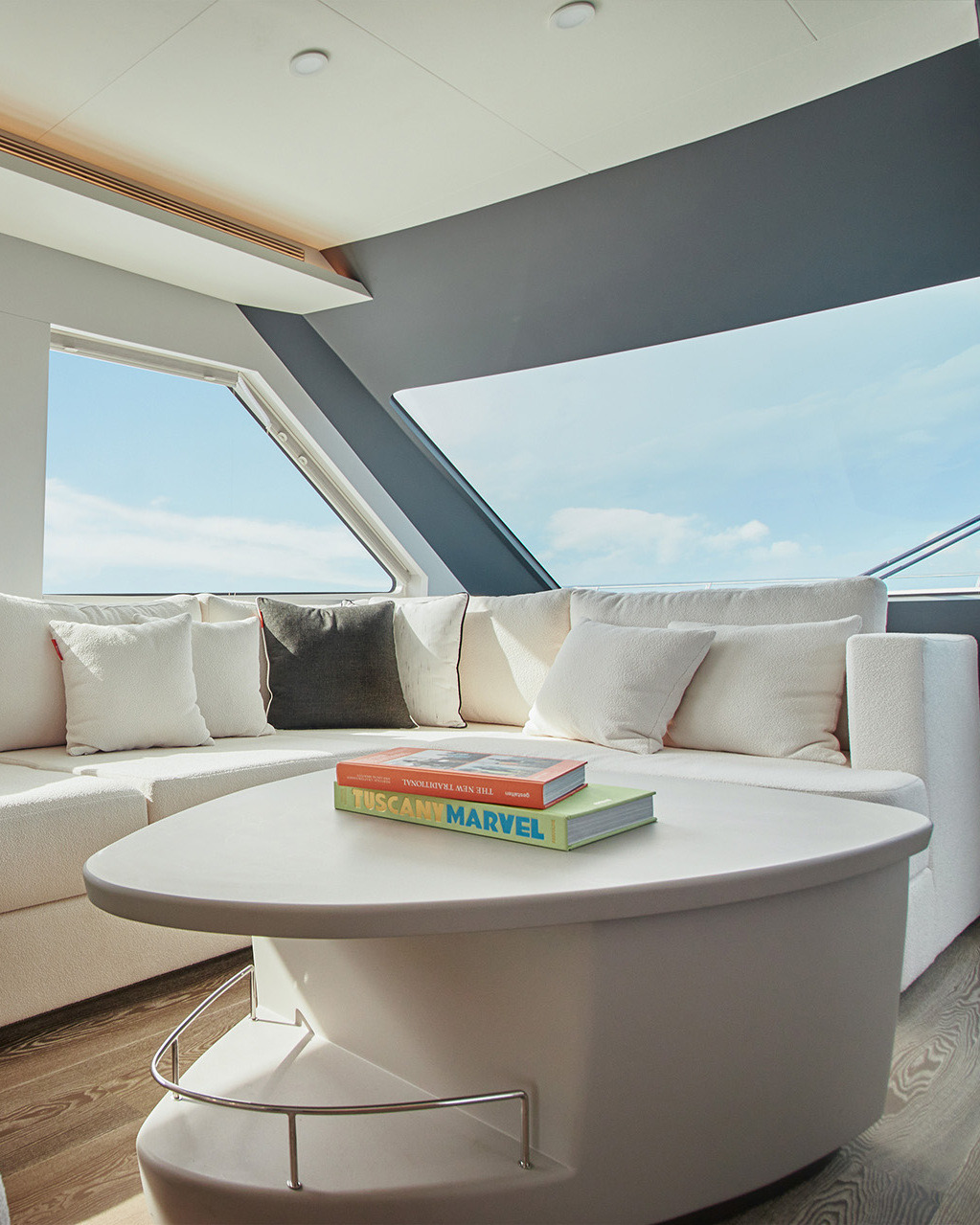 U-shaped sofa with a white table in a yacht salon beside large windows